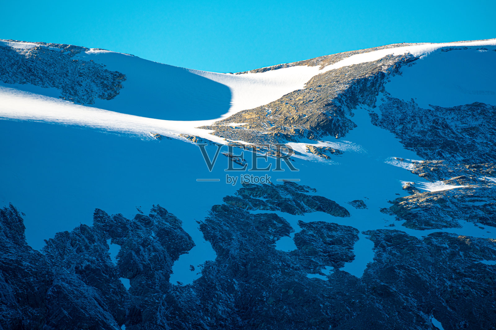 山间的小木屋，山峰白雪皑皑，天空湛蓝，色彩斑斓。照片摄影图片