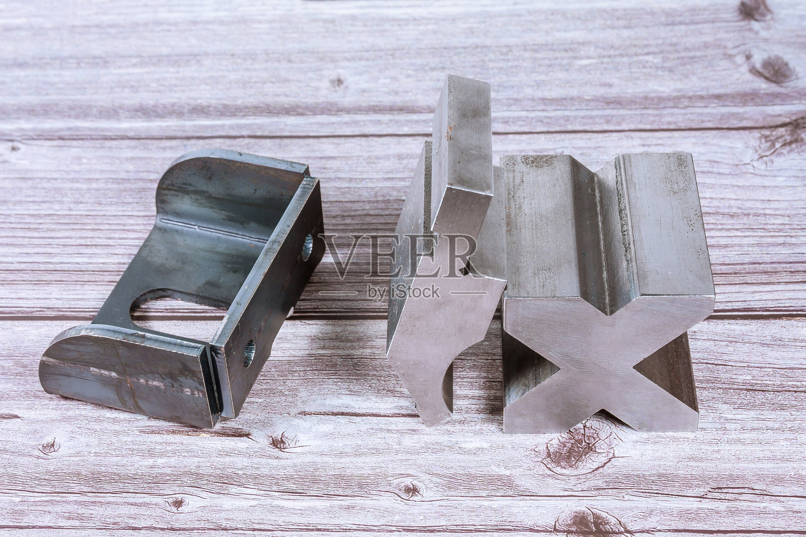 板材金属弯曲工具和设备上的一个木制背景。弯曲工具，冲压制动冲床和模具。照片摄影图片