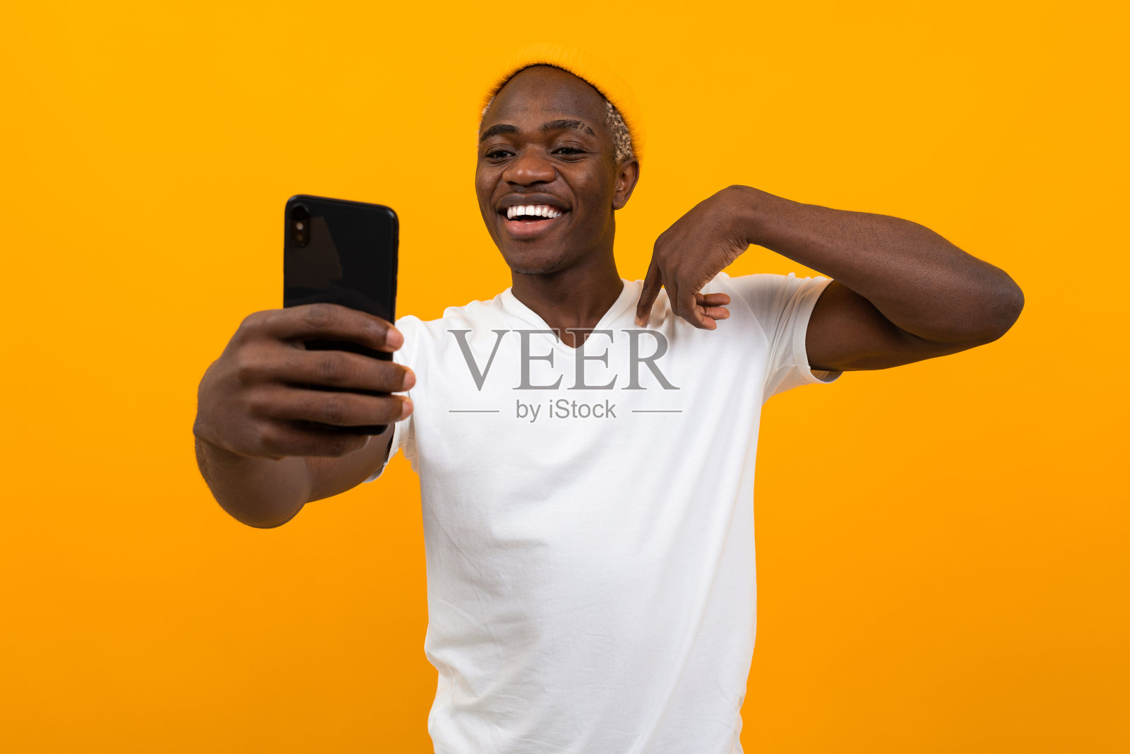 英俊的非洲黑人男子自拍手机上的橙色背景与拷贝空间照片摄影图片