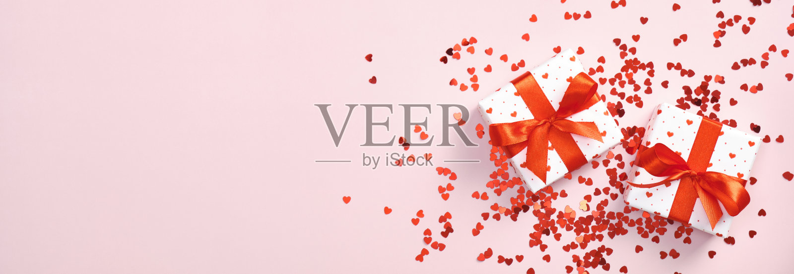 白色礼盒与红色丝带蝴蝶结和红色心形的五彩纸屑在柔和的粉红色背景。情人节横幅和礼物。母亲节礼物，生日惊喜。爱情,浪漫的概念。照片摄影图片