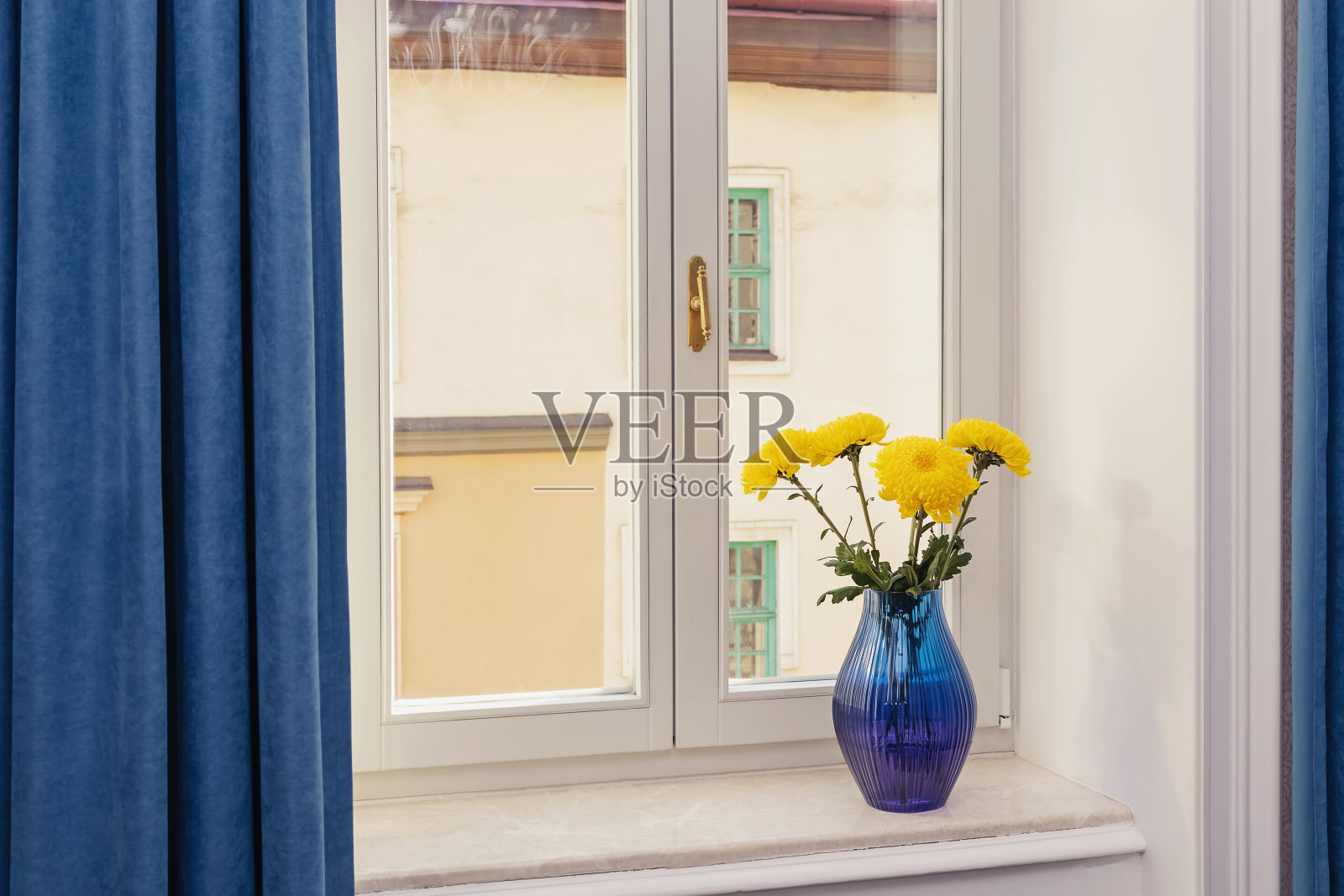 窗台上蓝色花瓶里插着黄色的花照片摄影图片