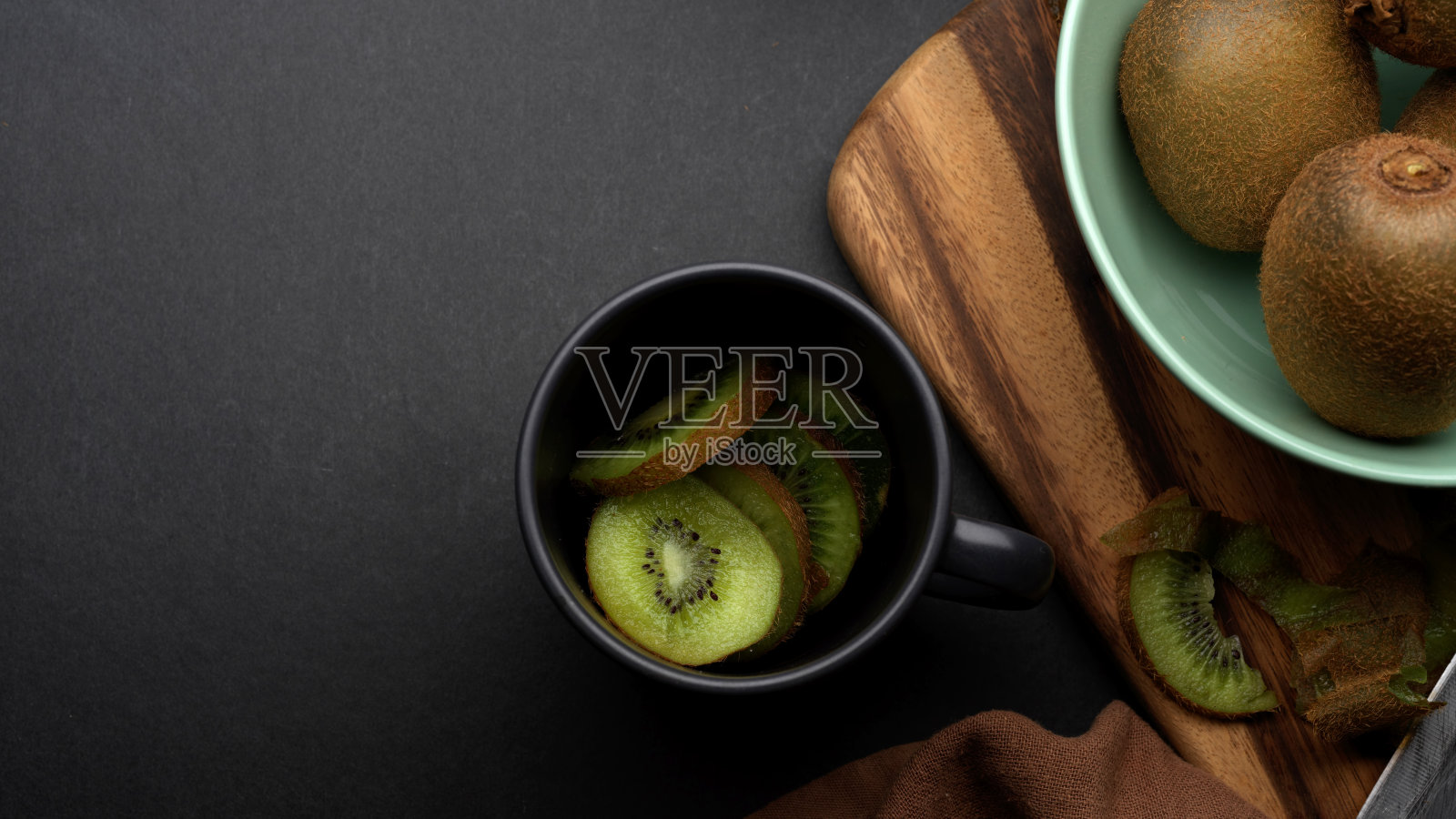 把新鲜的猕猴桃切片放在瓷杯里放在餐桌上，把整个猕猴桃放在碗里照片摄影图片