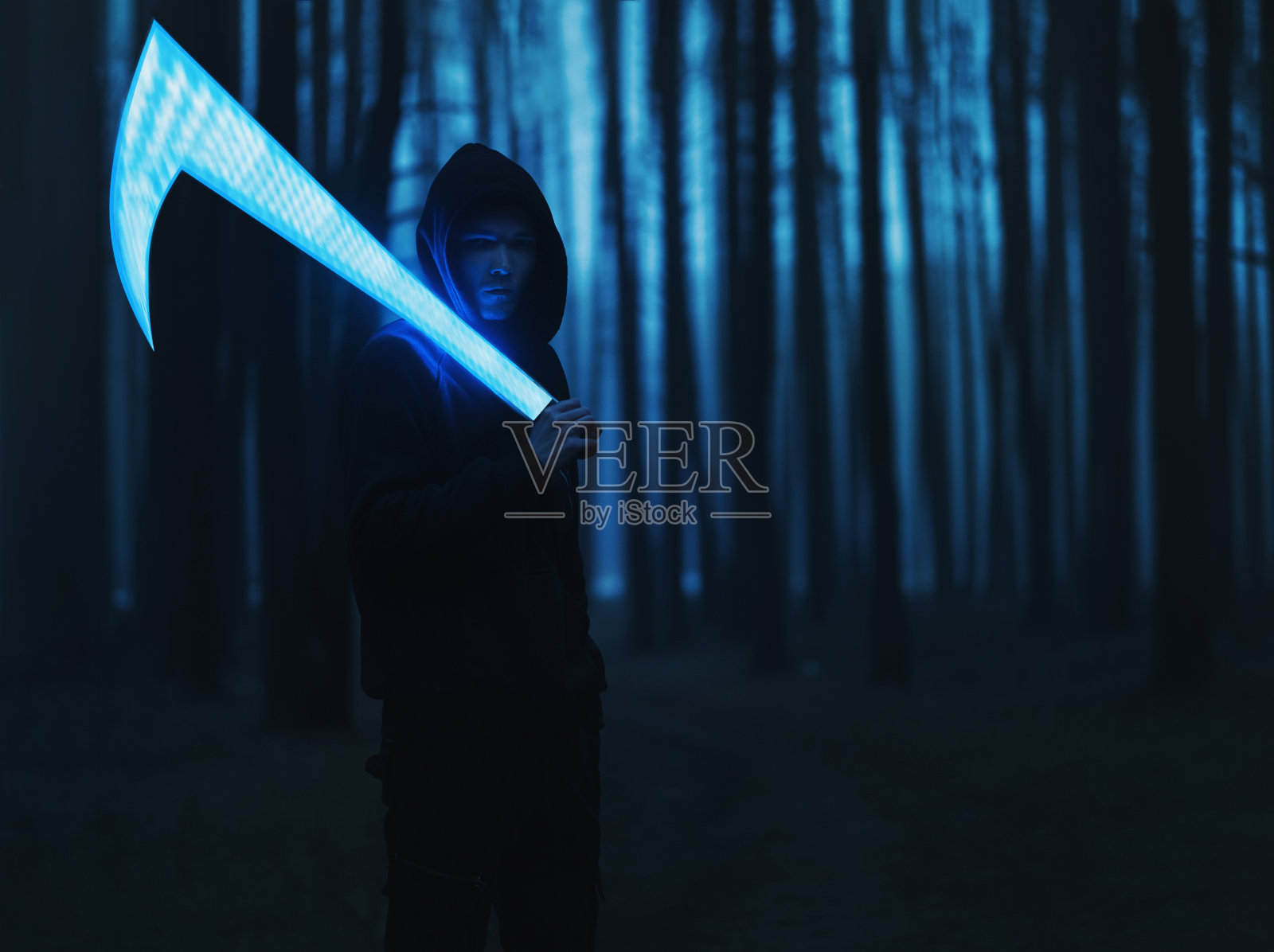 照片艺术，一个男人在黑暗的迷雾森林里拿着一把发光的镰刀或剑。幽灵猎人照片摄影图片