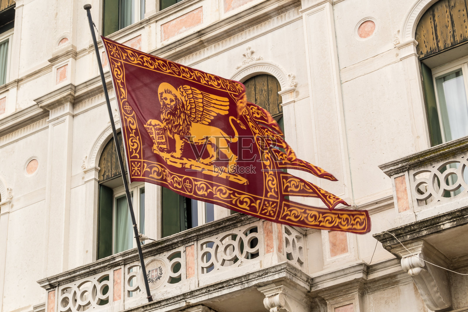 威尼斯旗与翼狮和古老的威尼斯建筑的背景。多云的冬日。照片摄影图片