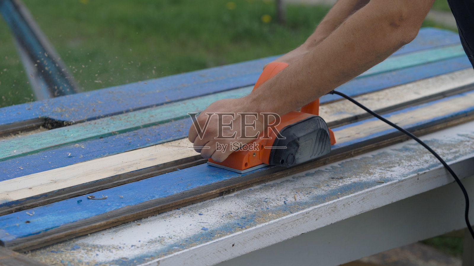 一个工人的手用一个工具在木头上。电子衬衫和旧板照片摄影图片