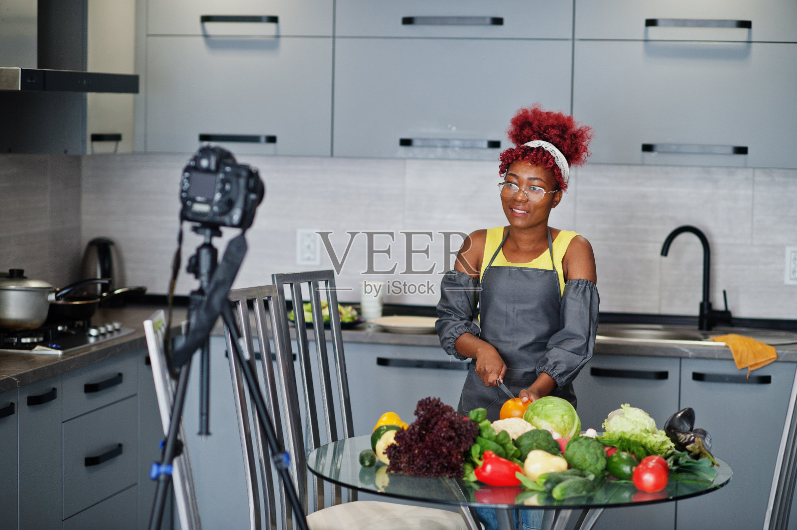 非洲裔美国妇女拍摄她的博客广播关于家庭厨房的健康食品。照片摄影图片