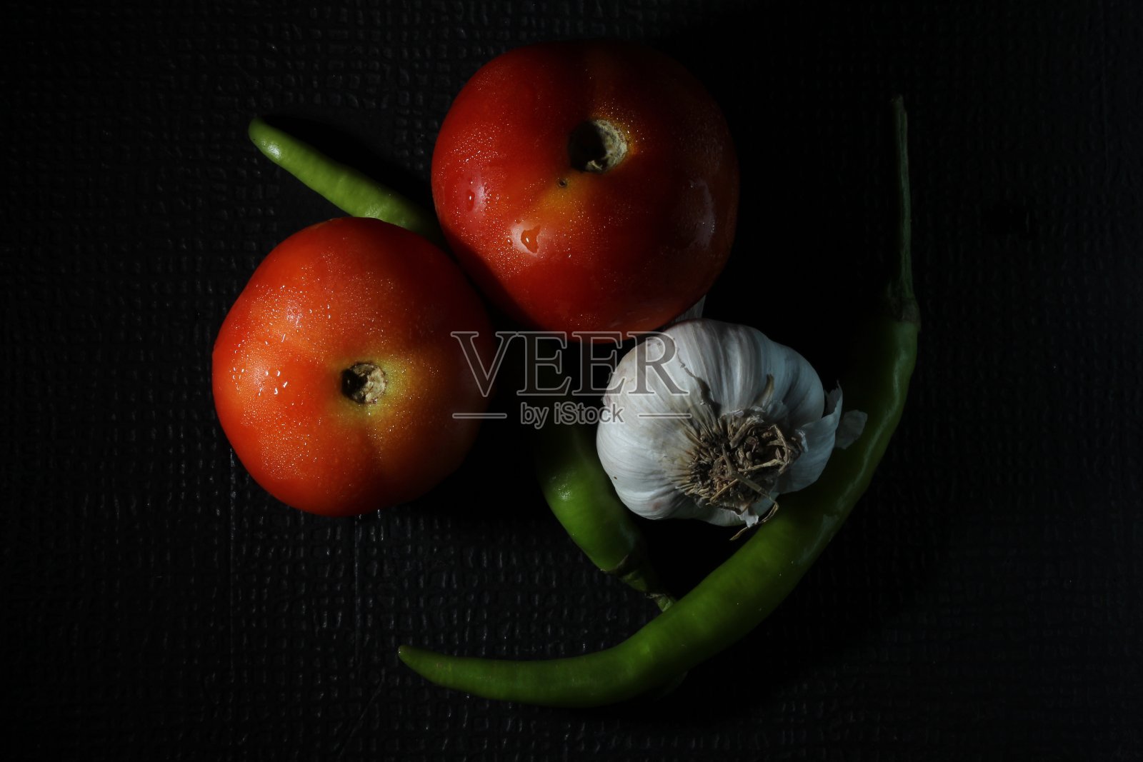 绿色的辣椒，大蒜，洋葱，番茄和咖喱叶被孤立在黑色的背景。成分的概念。辛辣的青椒和新鲜成熟的蕃茄在黑色的背景下。照片摄影图片