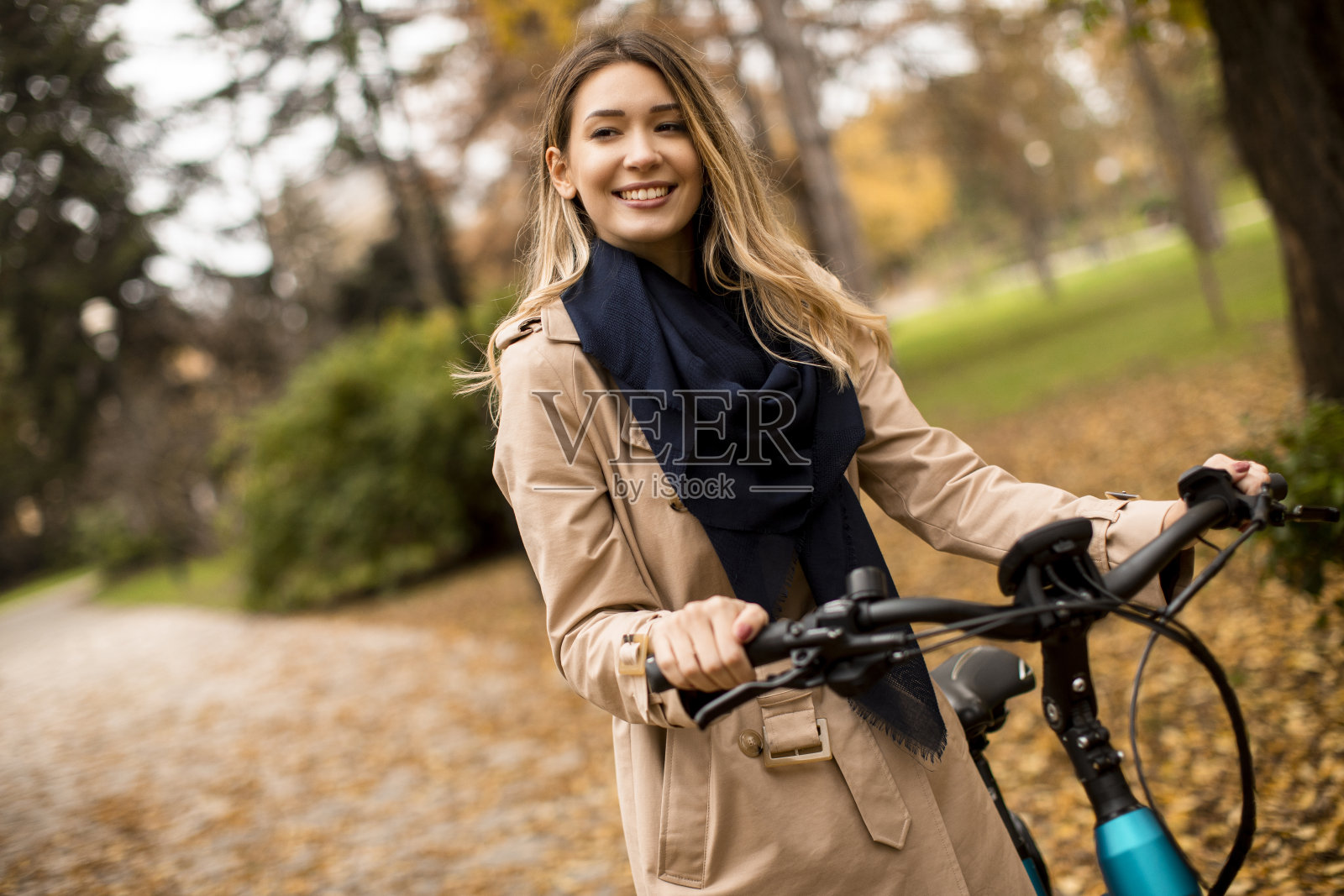 年轻女子骑着电动自行车在秋天的公园里照片摄影图片