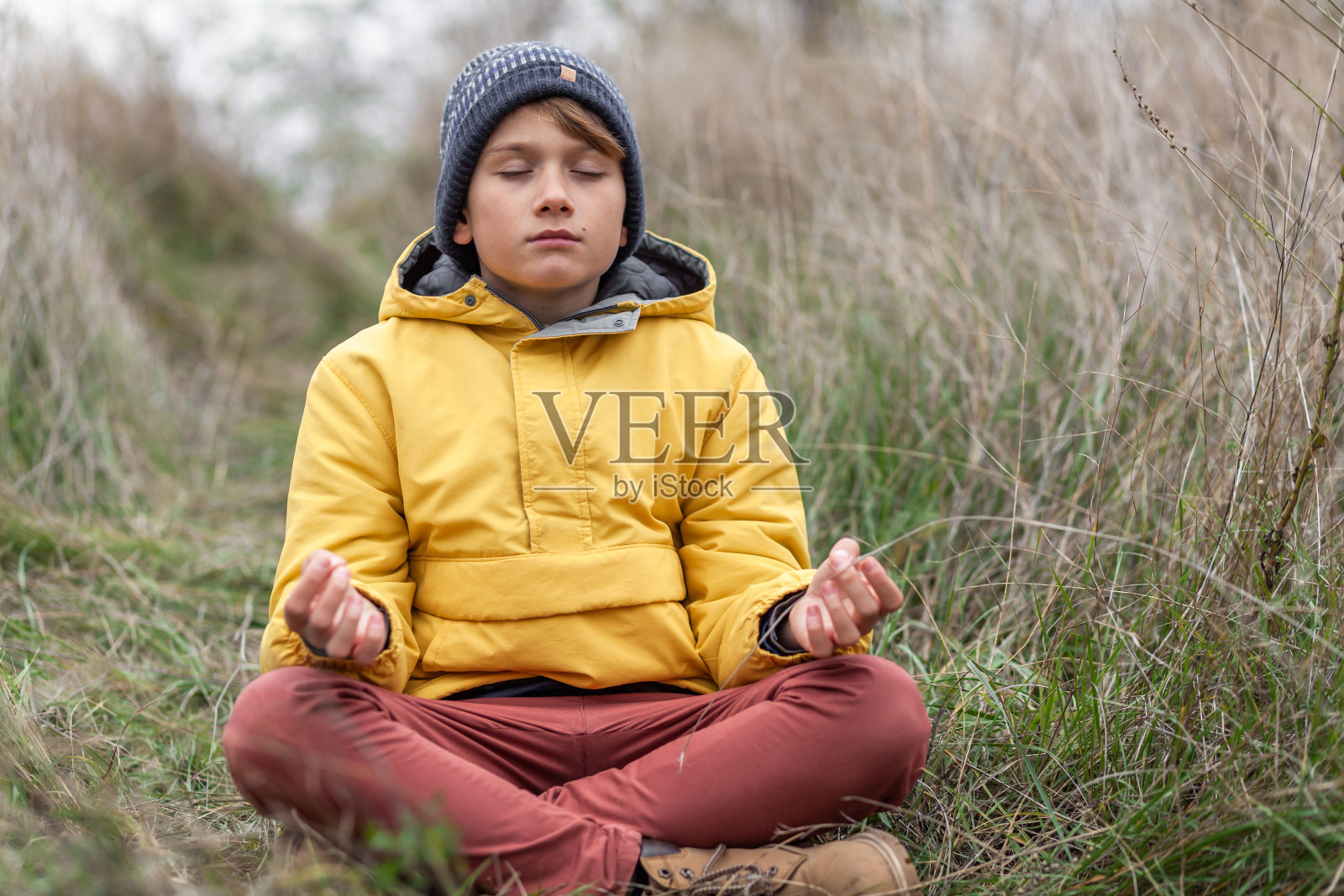 秋天的一天，小男孩在草地上练习瑜伽。照片摄影图片
