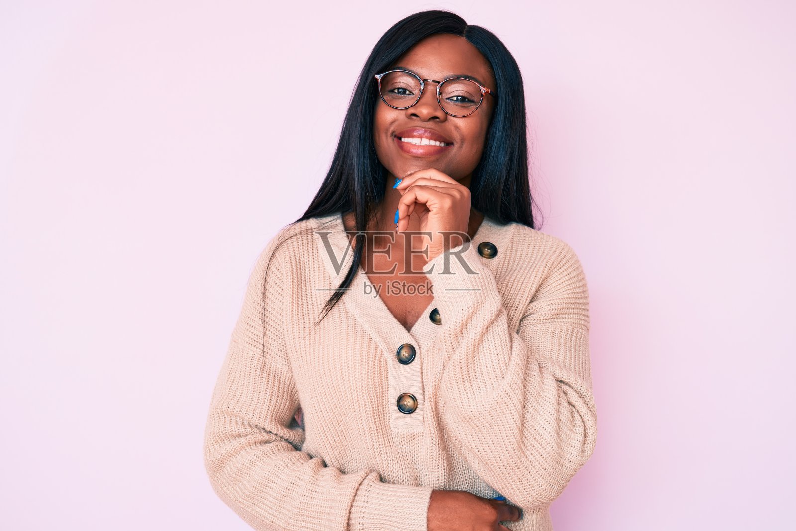 年轻的非洲裔美国妇女穿着休闲衣服微笑着看着镜头，双臂交叉，手放在下巴上。积极的思考。照片摄影图片
