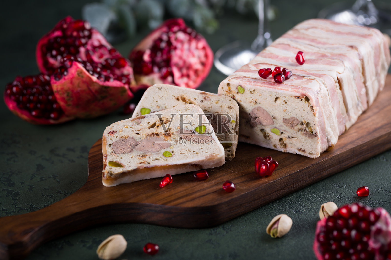 将美味的陶罐切在木切板上，以石榴籽为底，以绿色为底。圣诞小吃，开胃菜，复印空间照片摄影图片