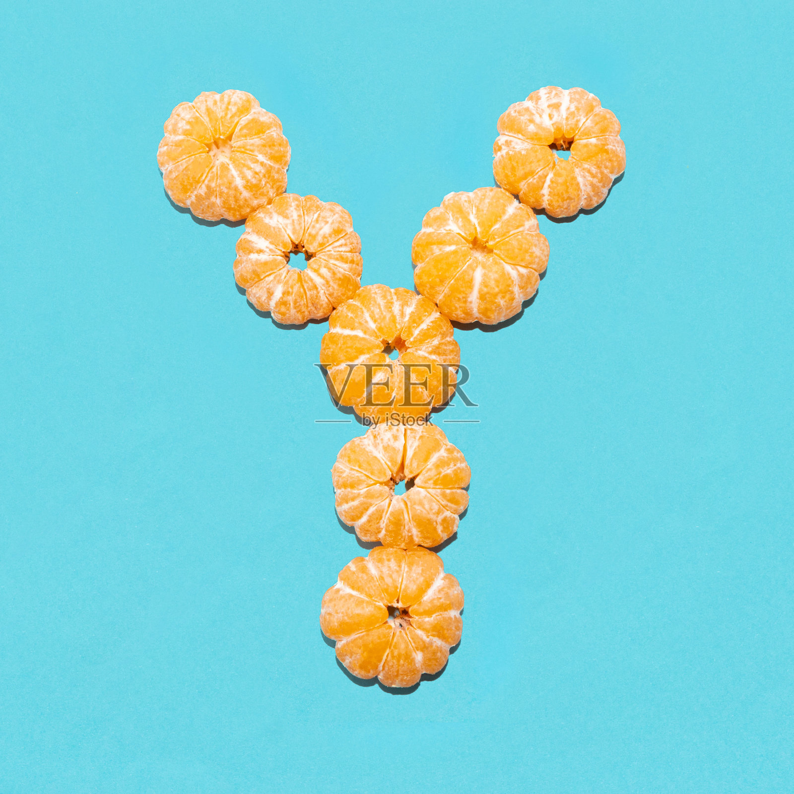 蓝色背景下去皮的橘子上的字母Y的创意布局。Flatlay。照片摄影图片