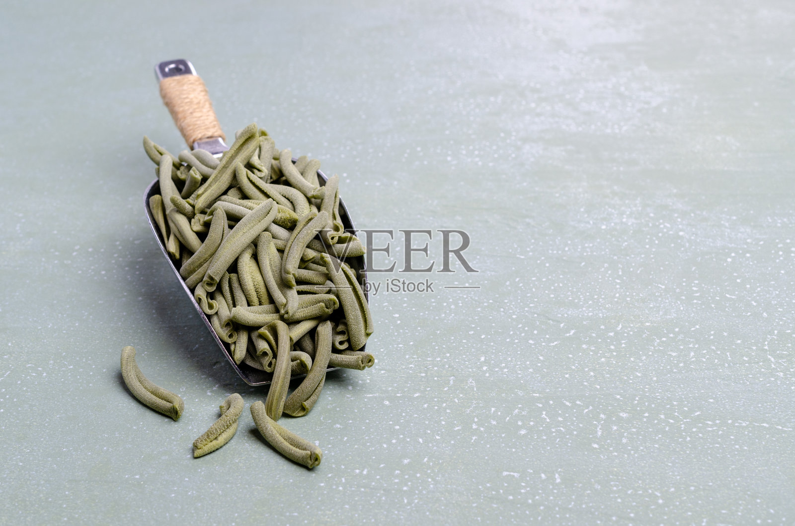 金属勺装的绿色干意面照片摄影图片