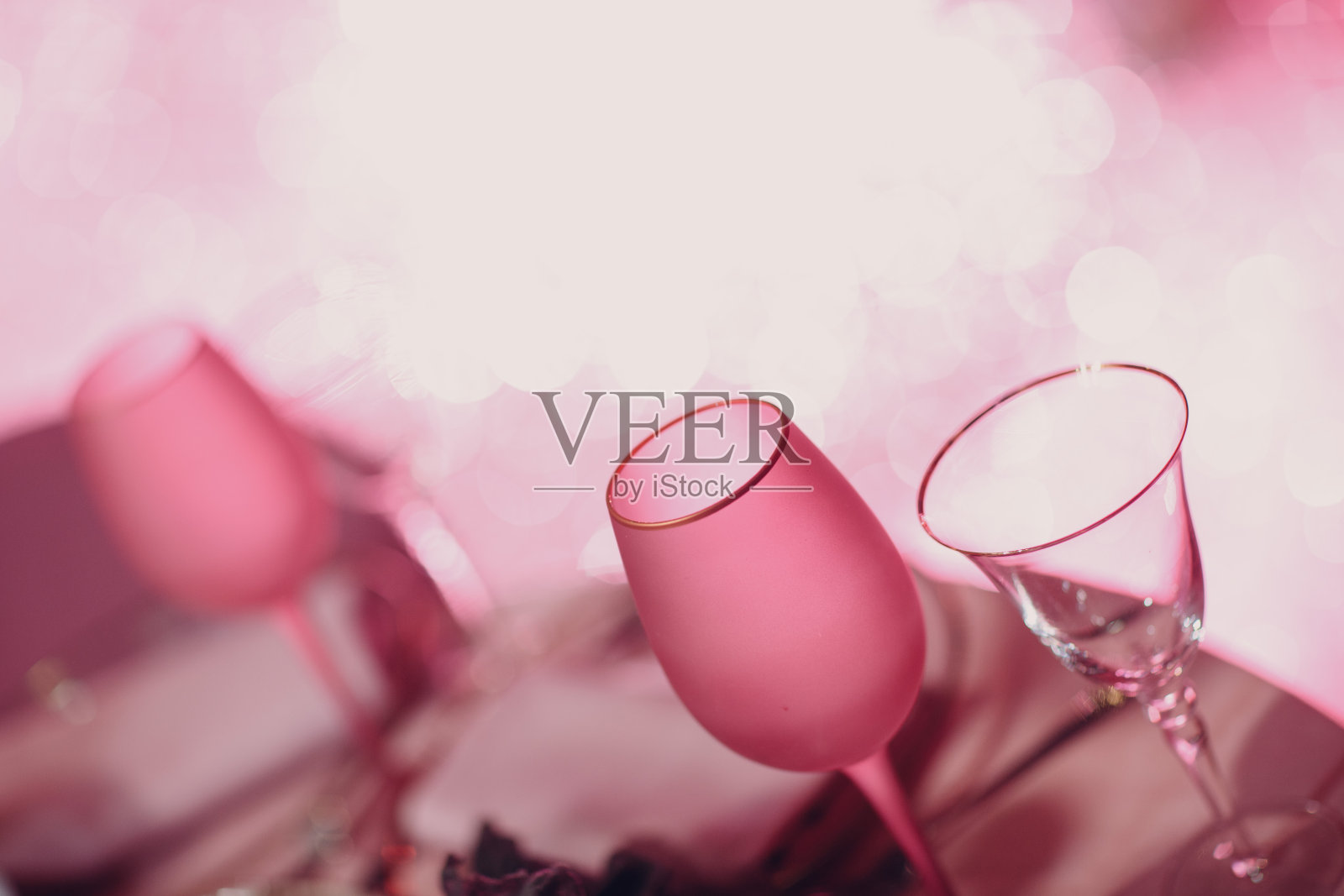 两个空的香槟酒杯，桌上放着粉红色的香槟，背景是闪闪发光的散景灯照片摄影图片