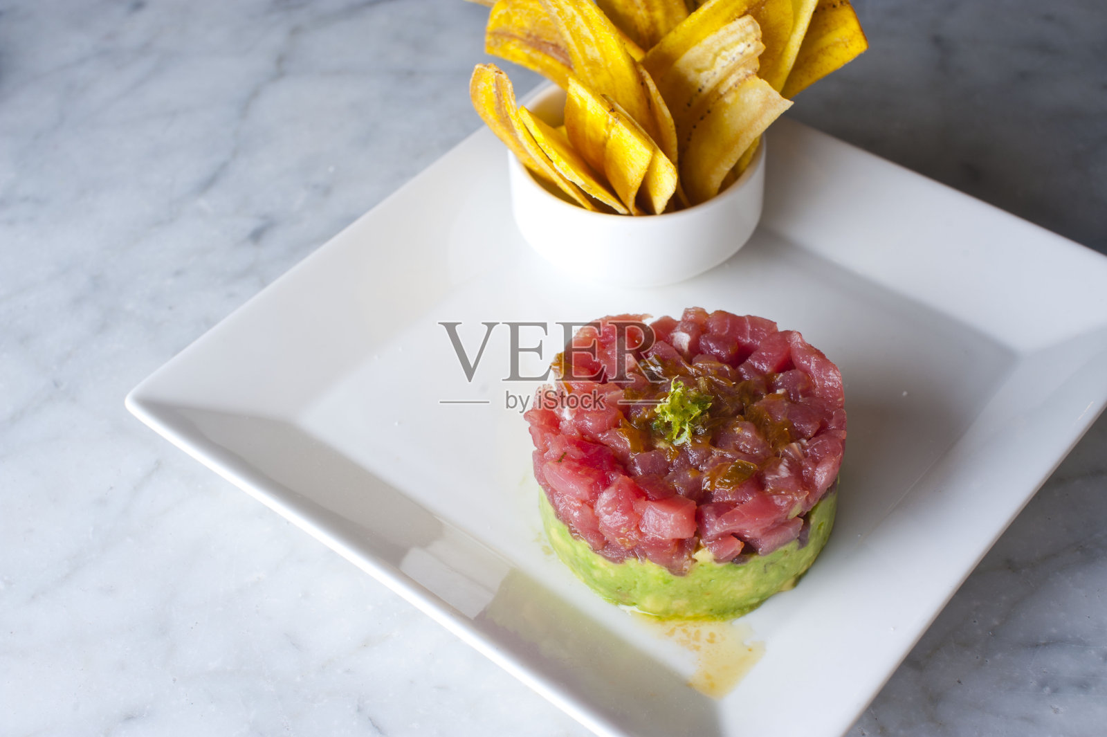 金枪鱼鞑靼。经典的美国餐厅或小酒馆开胃菜经典。寿司级的金枪鱼，切丁，混合鸡蛋，红洋葱，橄榄油，柠檬汁，大蒜和酸豆。和蒜蓉面包一起吃。照片摄影图片