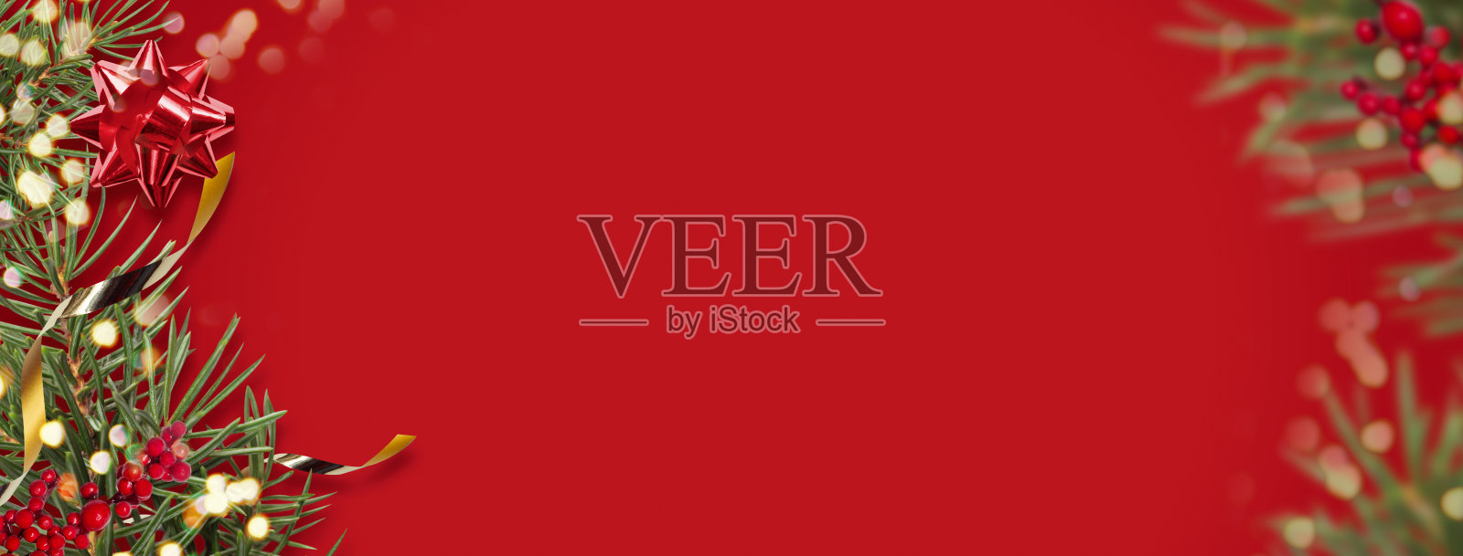 圣诞横幅与树枝与金色的礼物丝带，复制空间，散焦在红色的背景。宽格式照片摄影图片