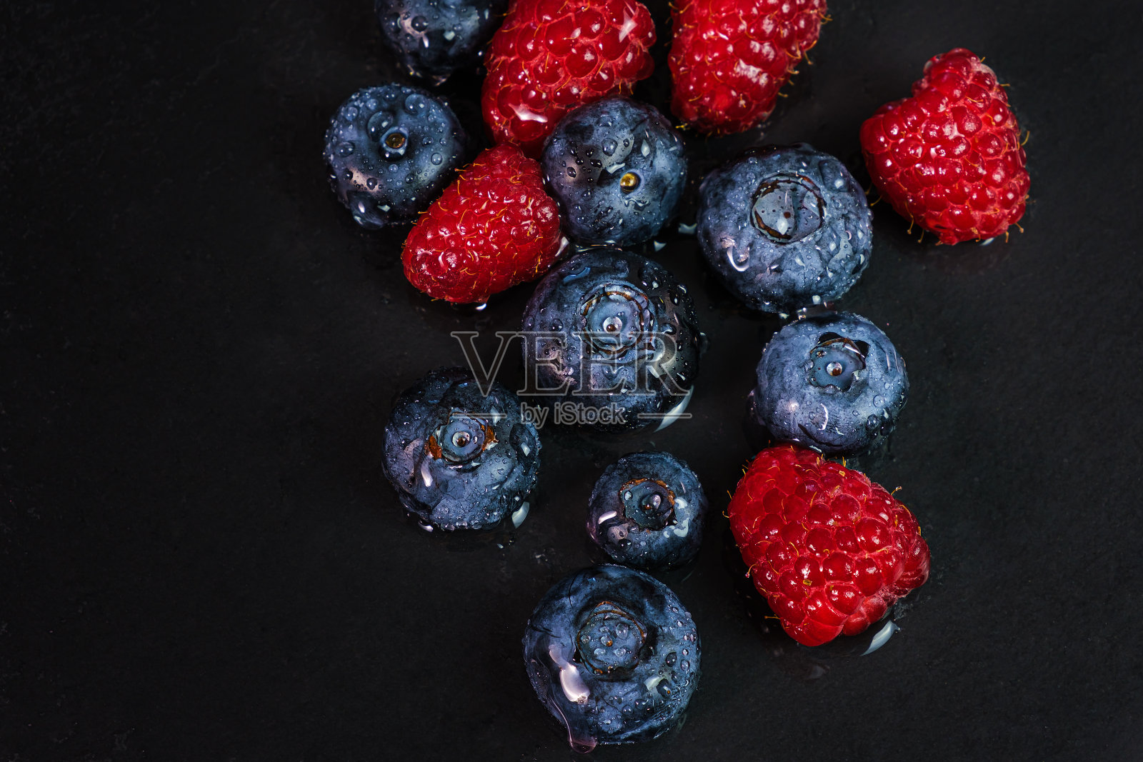 蓝莓和覆盆子孤立在黑色背景。生浆果混合孤立。照片摄影图片