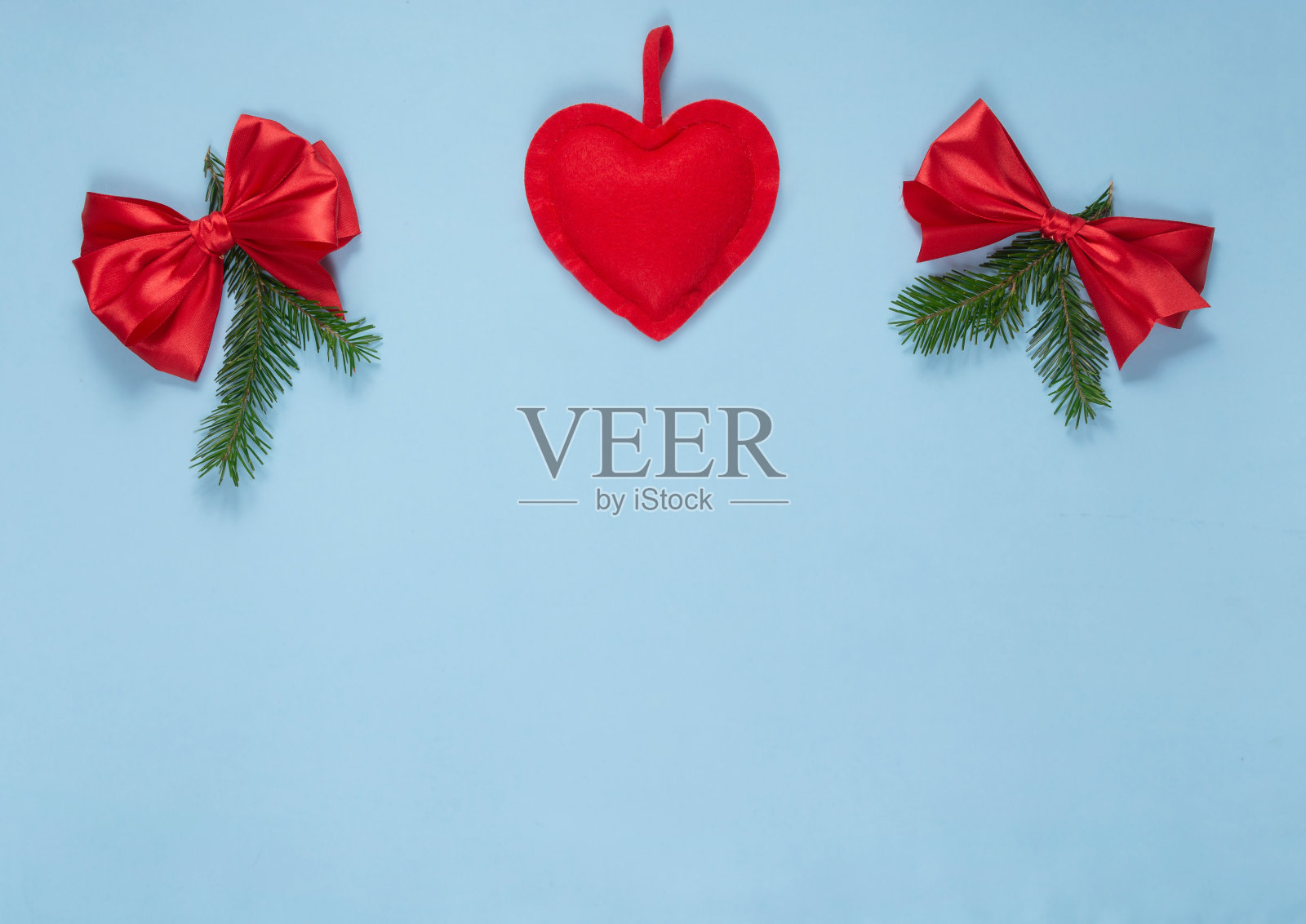 喜庆的蓝色背景，一颗心和红色蝴蝶结。新年和圣诞节的概念照片摄影图片