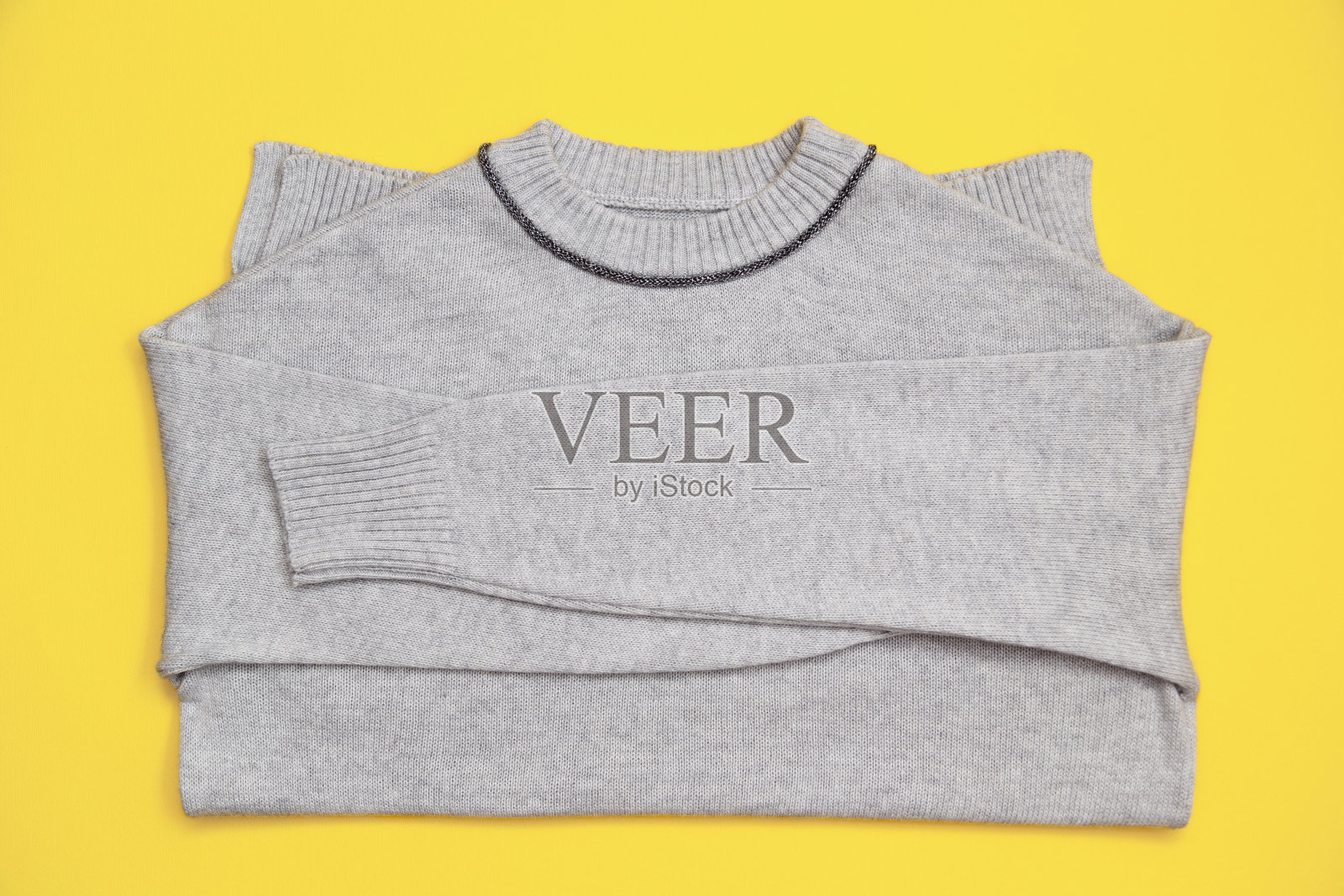 针织套衫在时髦的灰色颜色在一个黄色的背景在剥皮lay风格。2021年的颜色17-5104灰色和13-0647照明照片摄影图片