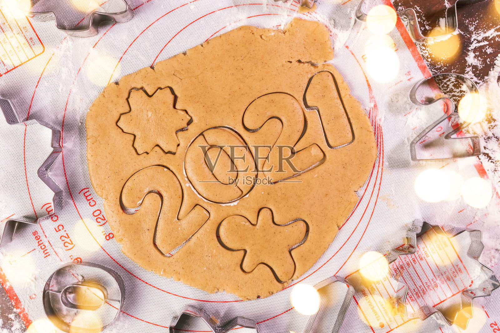 一个女人用手在黑板上切着2021年的饼干，上面撒着烘焙面粉。擀面杖、面粉和年画人物的形状。照片摄影图片