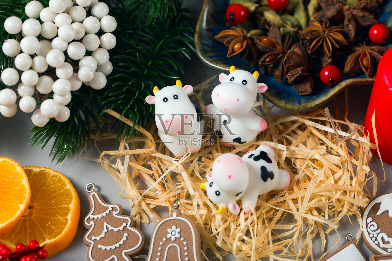可爱的玩具牛与一些圣诞装饰。用糖霜、八角种子、小豆蔻、云杉树枝、冬青浆果和其他新年装饰品制作的姜饼照片摄影图片