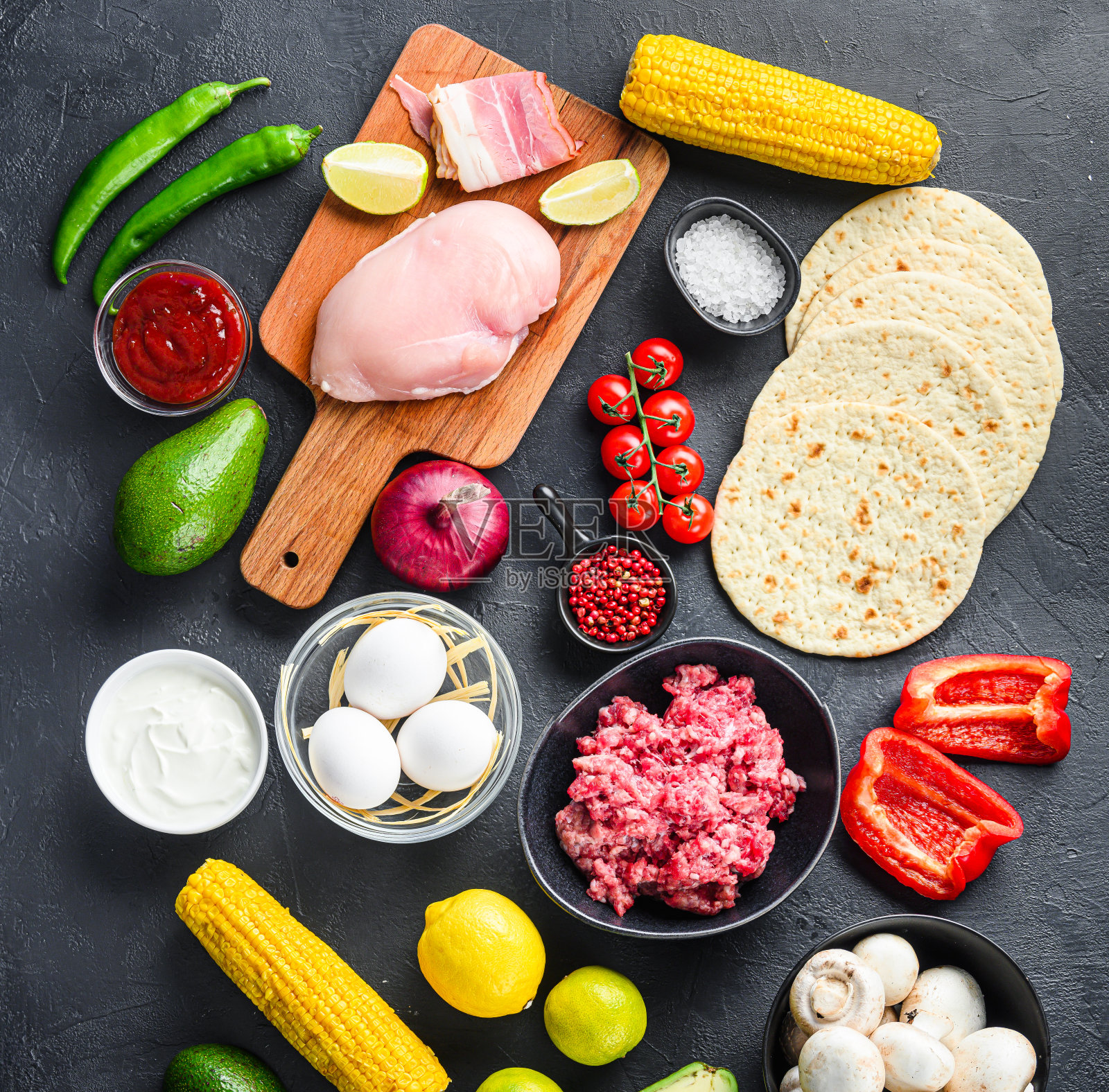 混合墨西哥食物背景，生的有机成分的玉米饼与鸡肉和牛肉，玉米玉米饼，莎莎，辣椒在黑色的背景，顶视图广场。照片摄影图片