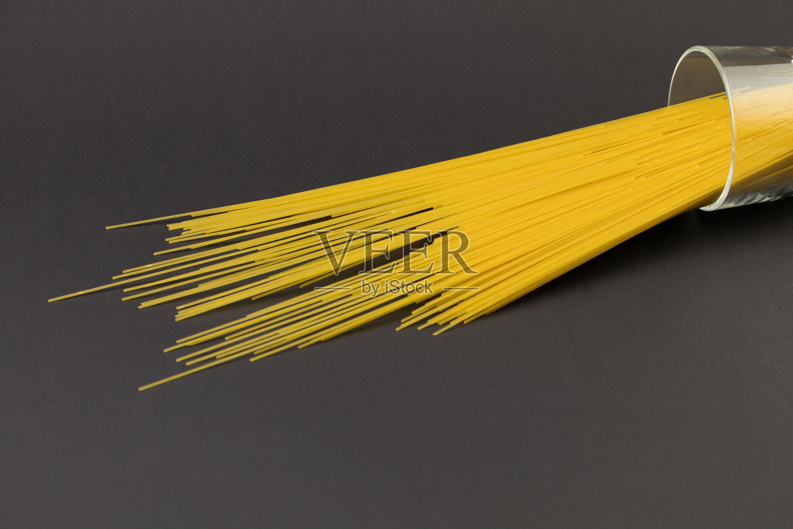 深色的背景上放着一个大杯子里的长通心粉照片摄影图片