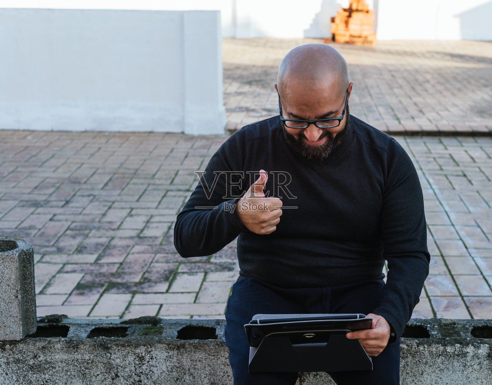 光头留胡子的男人通过视频会议向朋友打招呼照片摄影图片