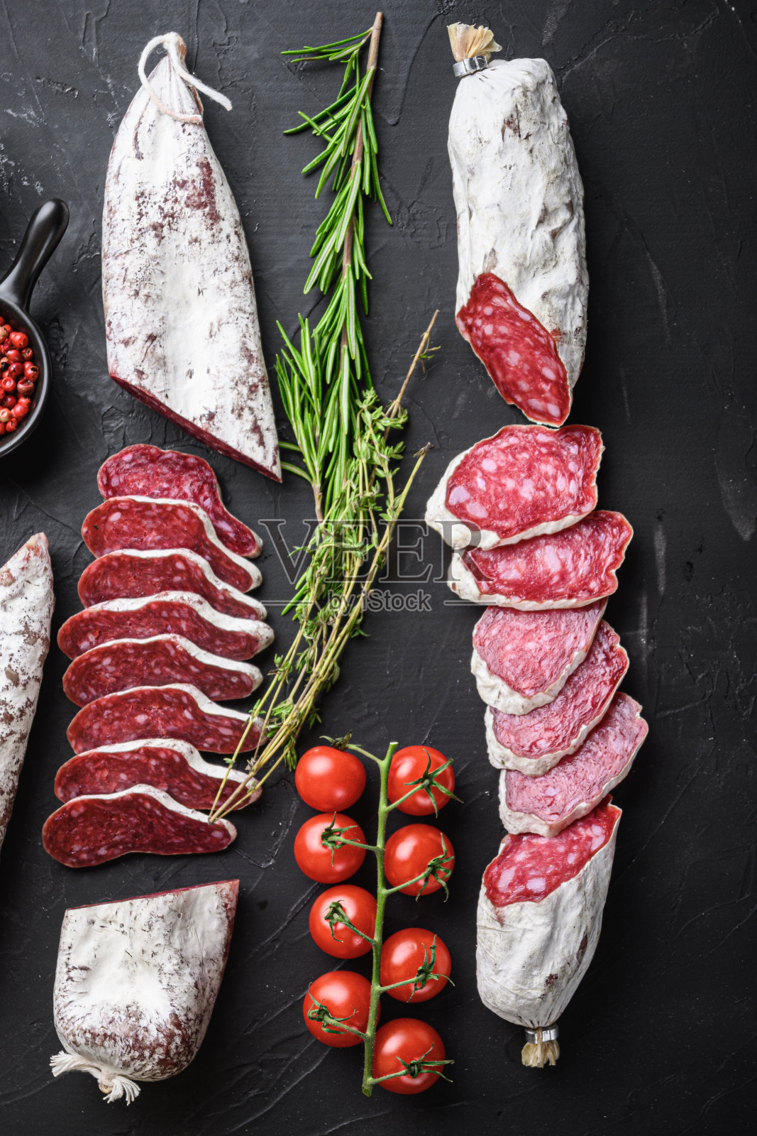 一套各种西班牙干腌腊肠片和整片，放在黑色的背景上，平铺照片摄影图片