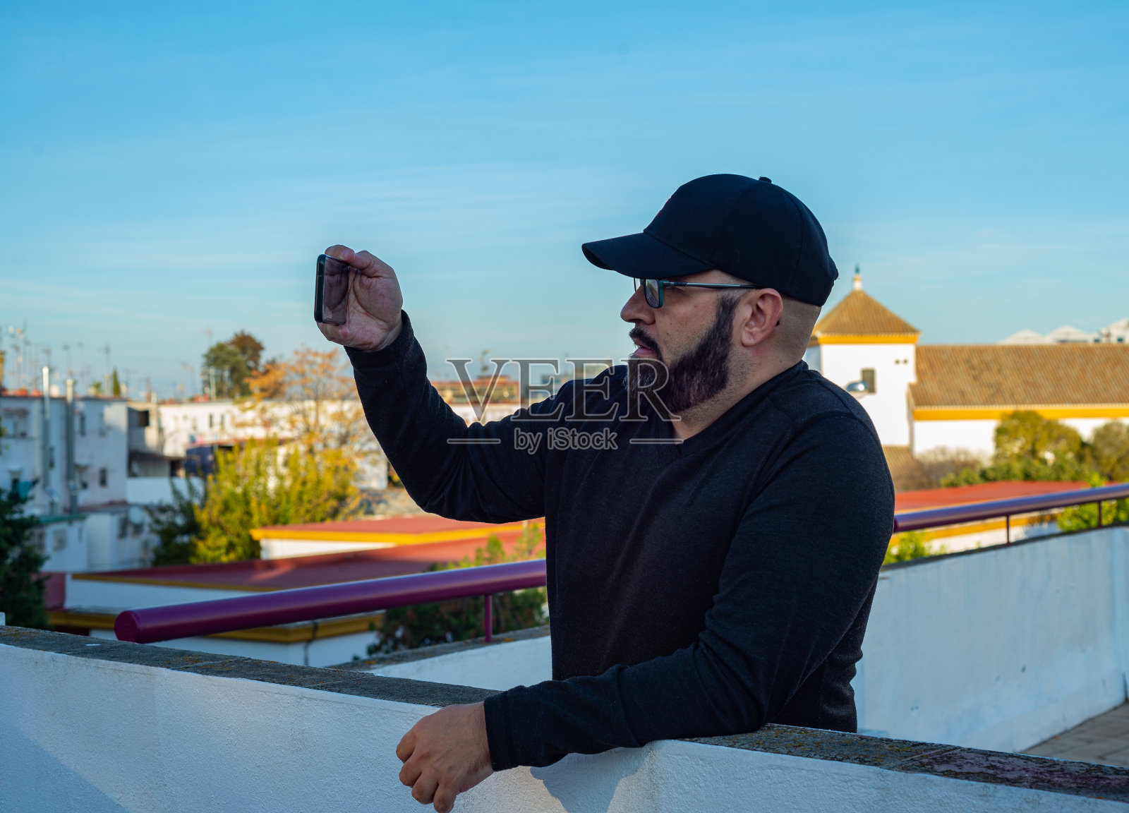 戴帽留胡子的男人在屋顶上拍照照片摄影图片