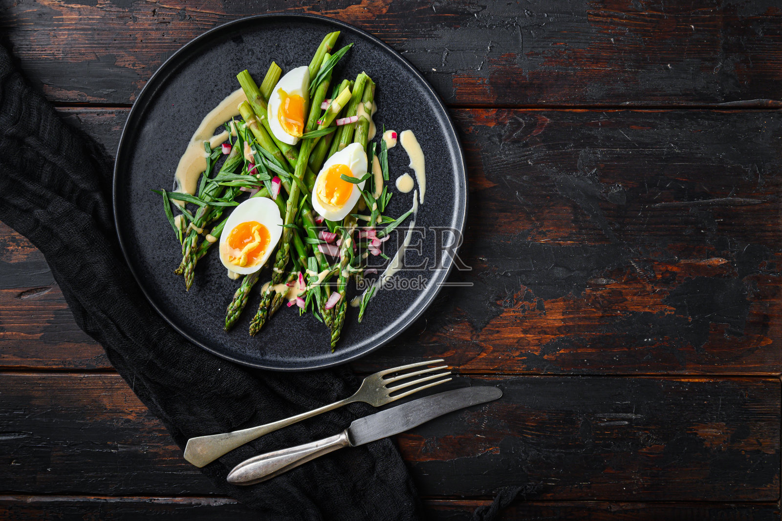 芦笋配鸡蛋，法式调味汁配第戎芥末，用红醋切碎的洋葱和龙舌兰放在旧的深色木桌上。照片摄影图片