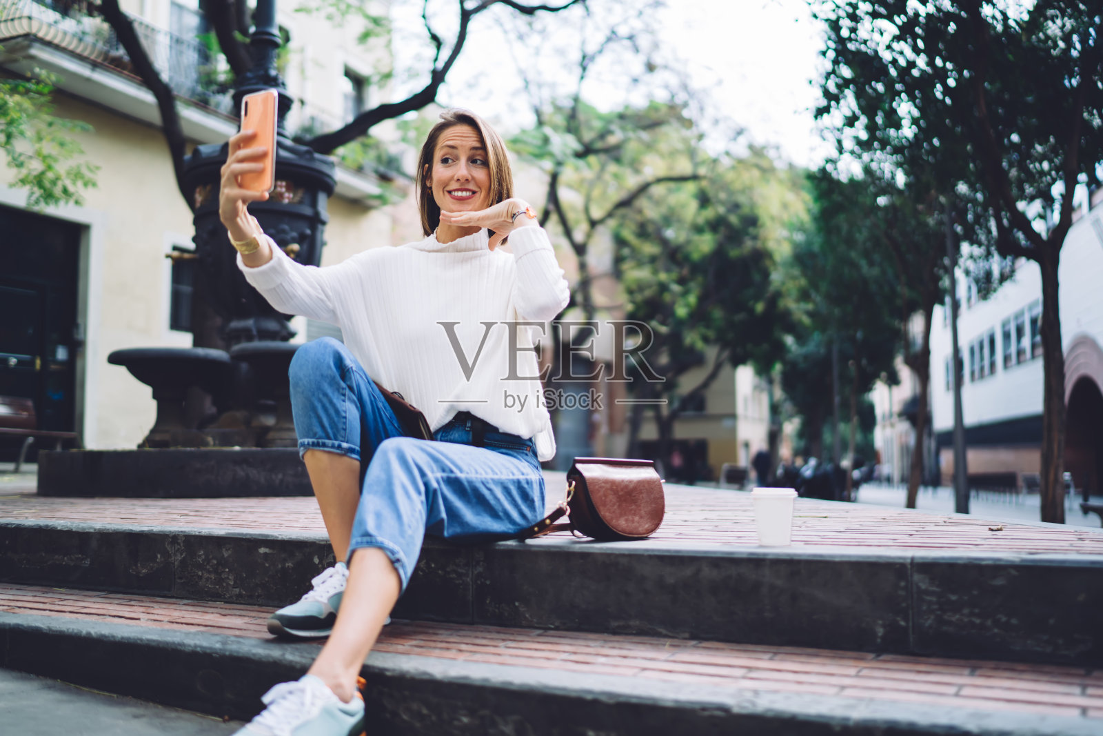 微笑的女游客在公园的楼梯上自拍照片摄影图片