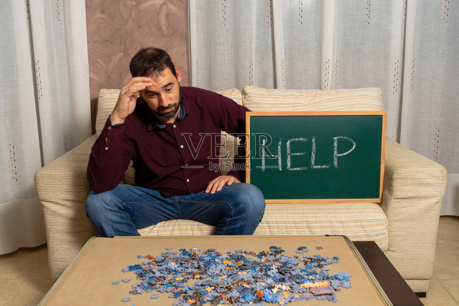 一个留着胡子的年轻人坐在家里的沙发上玩拼图游戏照片摄影图片