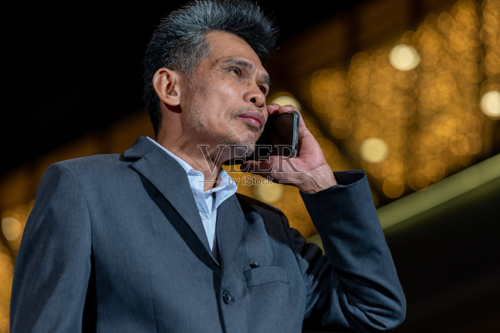 肖像亚洲资深商人穿黑色西装通过电话与客户做生意照片摄影图片