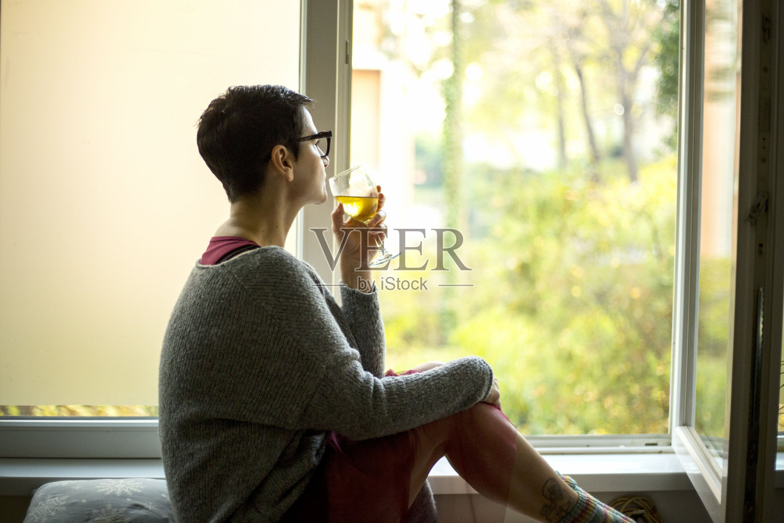 年轻女子坐在窗边喝白葡萄酒照片摄影图片