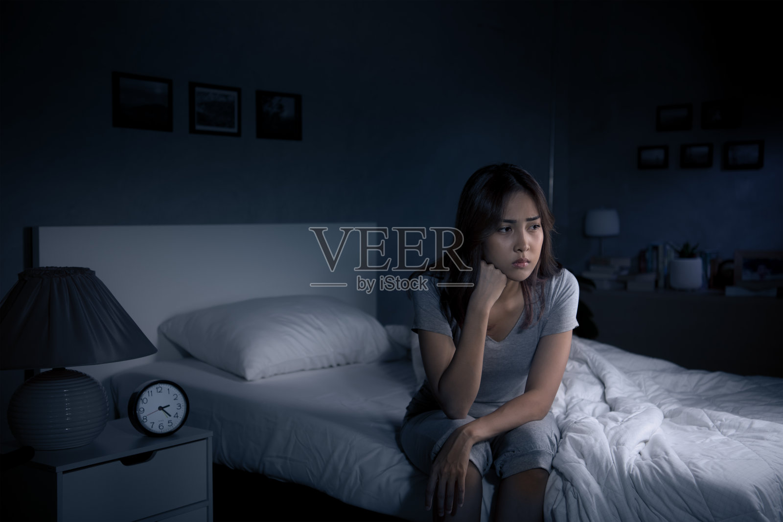 失眠的沮丧年轻亚裔女子坐在床上无法入睡照片摄影图片
