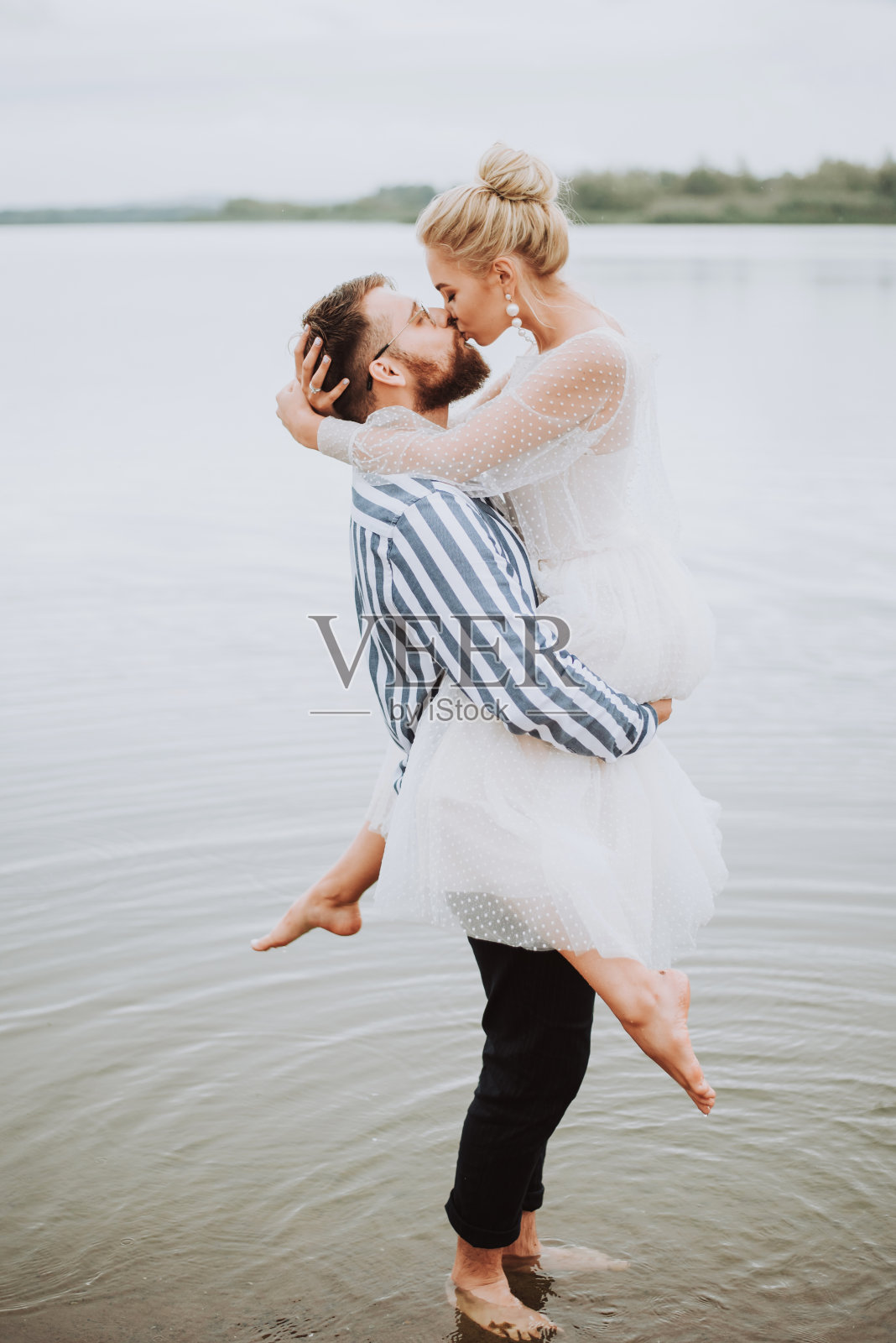 在海岸线上亲吻和拥抱的年轻新婚夫妇照片摄影图片