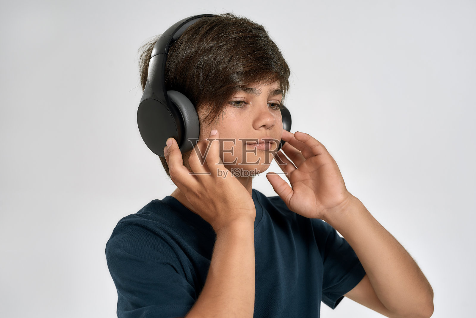 肖像的小运动男孩穿着运动服戴耳机，看着一边听音乐，站在孤立的白色背景照片摄影图片