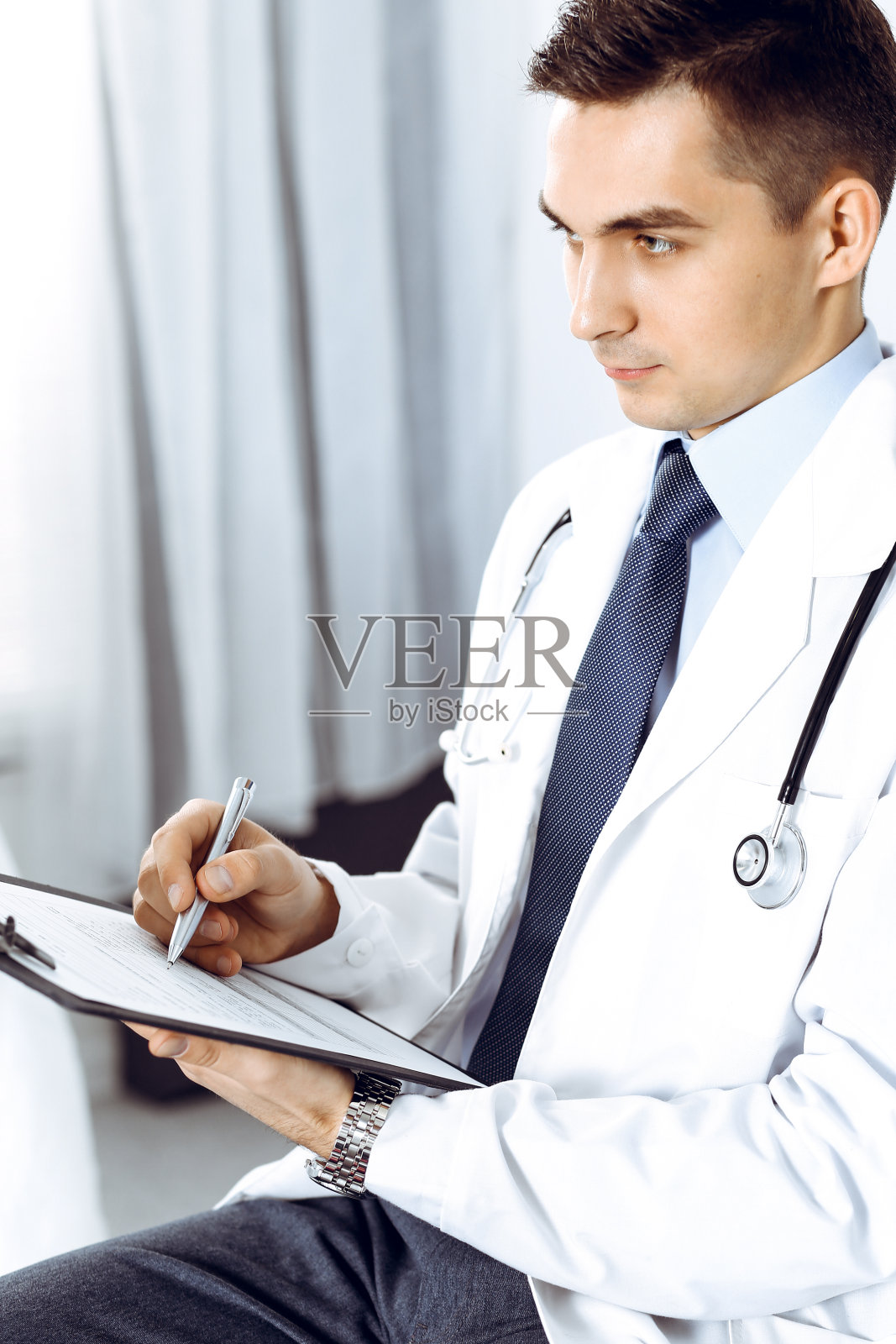 医生在写字板上填写医疗表格。医疗保健、医疗保险和病人服务理念照片摄影图片