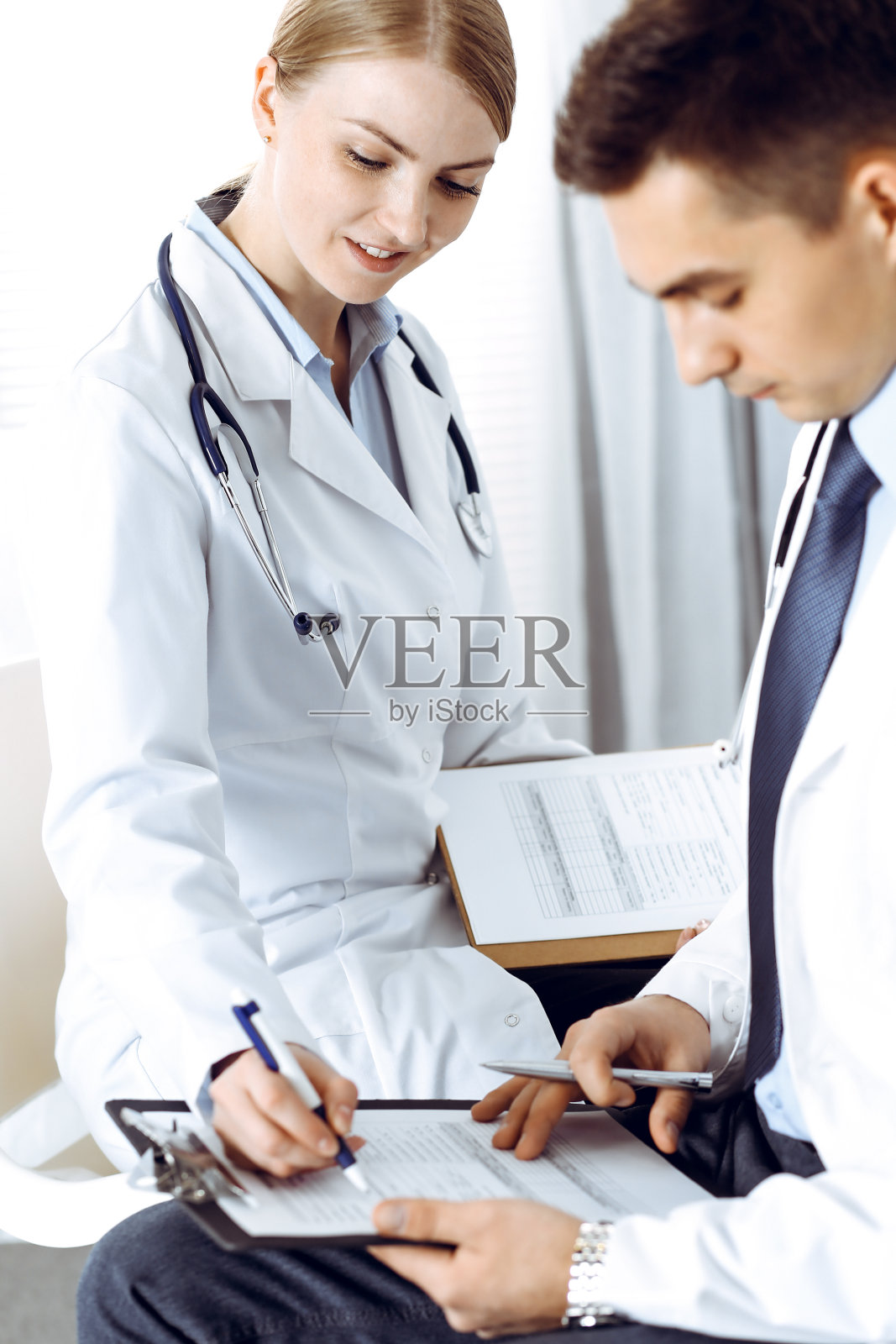 医生用剪贴板写论文。在医学会议上讨论药物治疗计划或学习的医生。医疗、保险和医学概念照片摄影图片