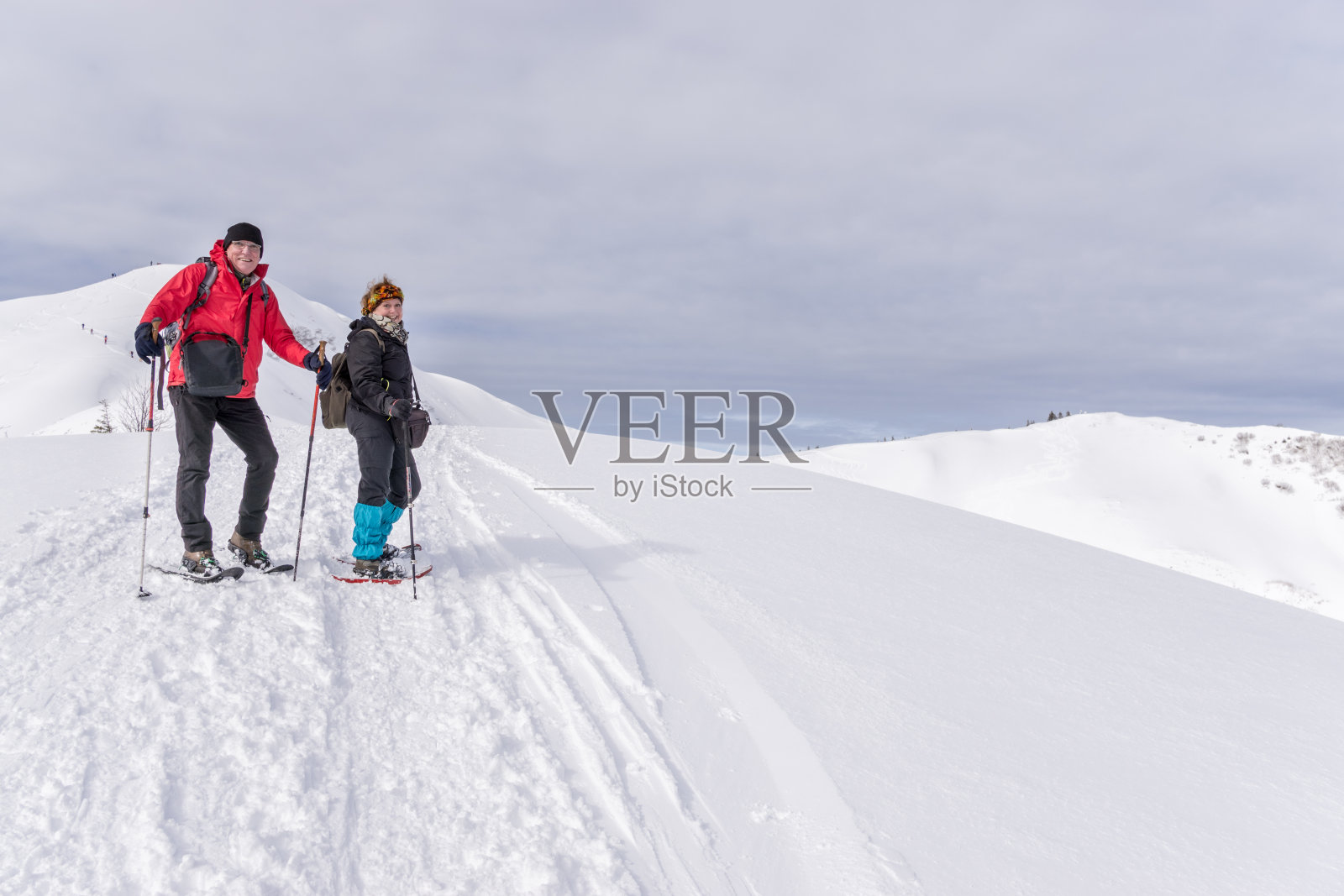 一对老年夫妇正穿着雪鞋在高山雪山中徒步旅行。Allgau,巴伐利亚,德国。照片摄影图片