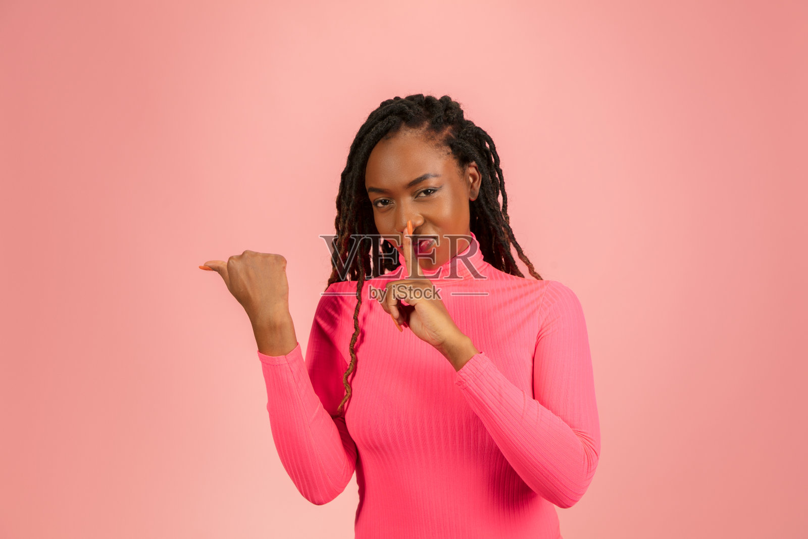 年轻的非裔美国妇女被孤立在粉红色的工作室背景下，面部表情。美丽的女性半长肖像与copyspace。照片摄影图片