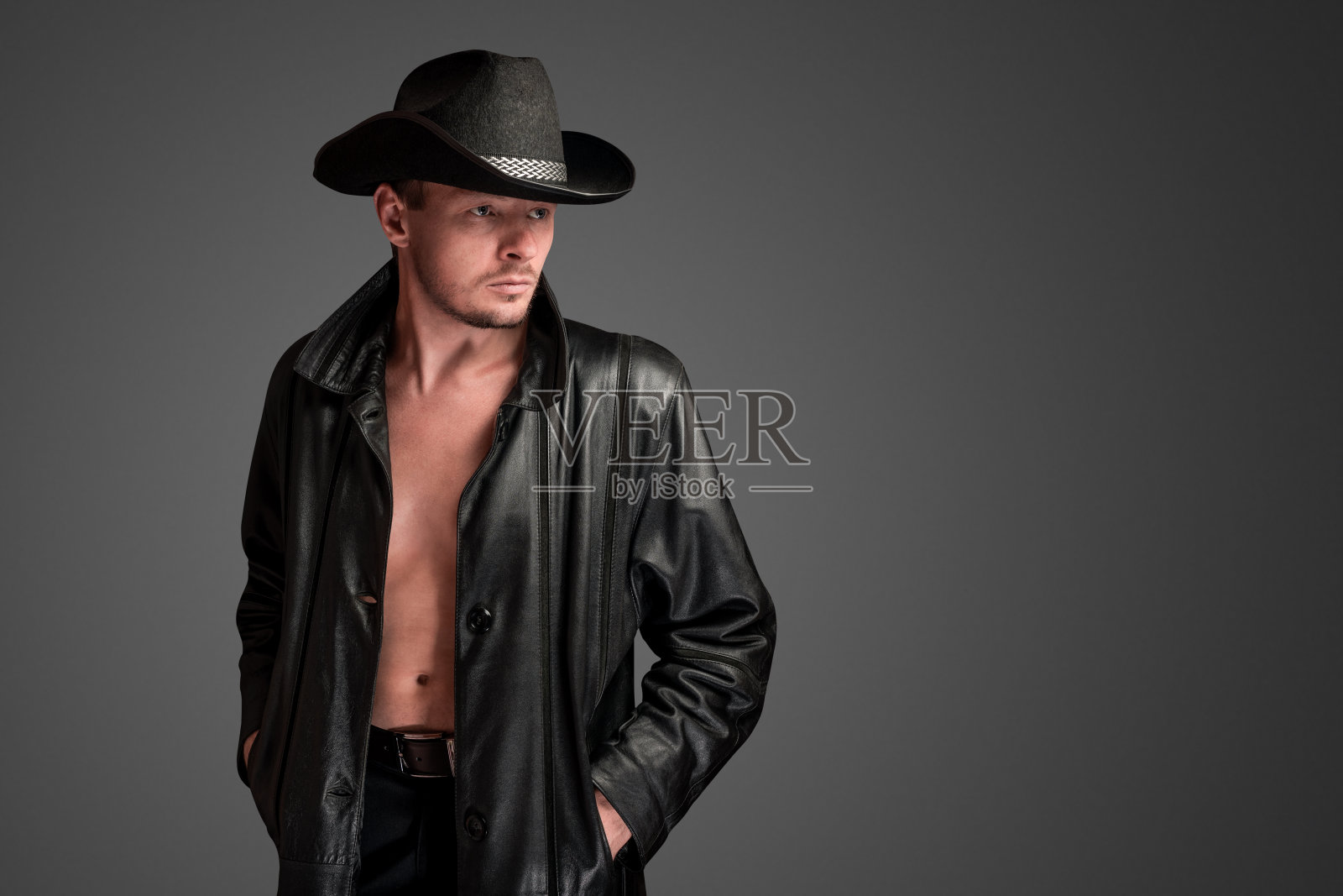 穿着皮夹克的牛仔看着他赤裸的身体。照片摄影图片