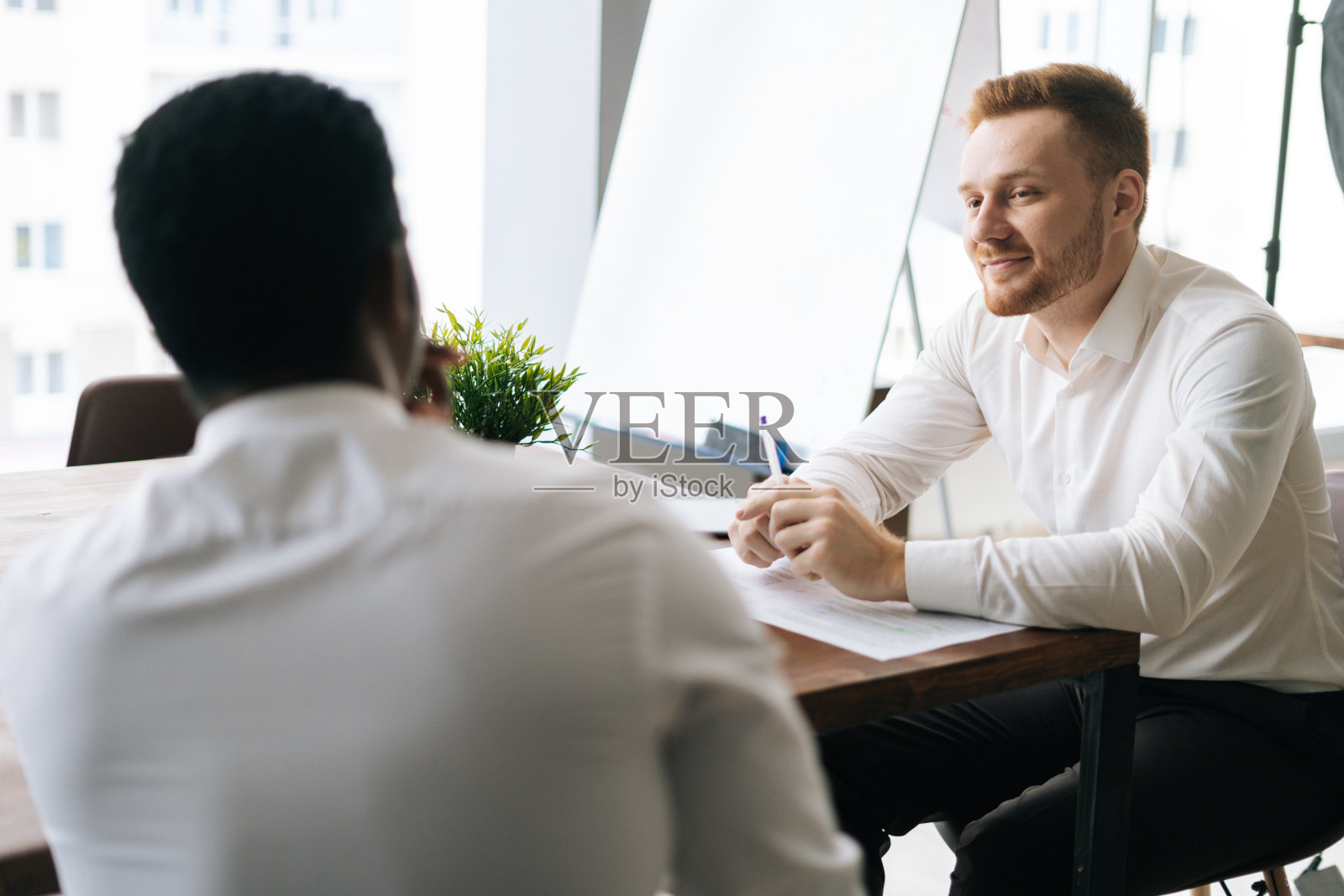微笑的商人听非洲商业伙伴谈论新项目坐在桌子前照片摄影图片