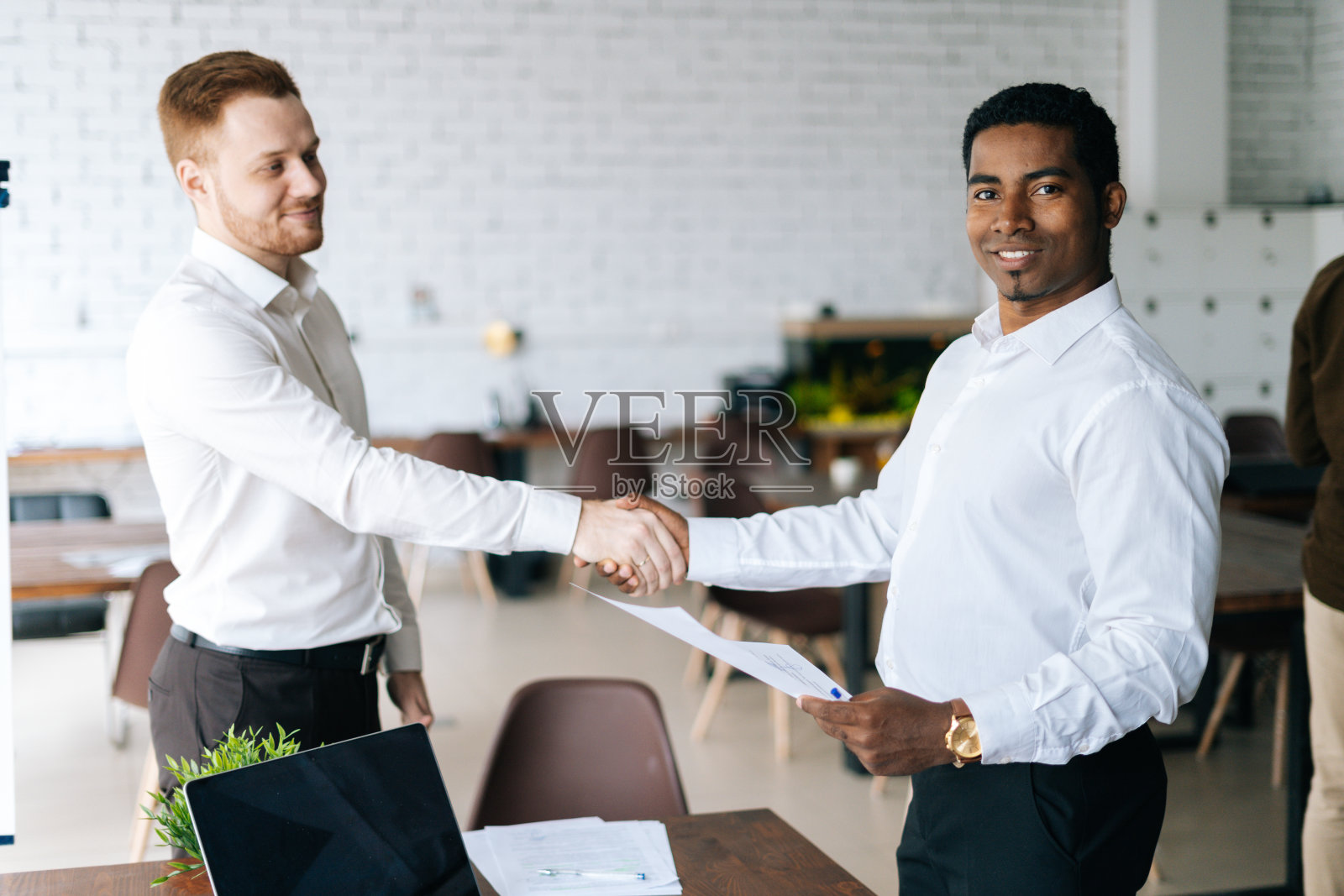 白人商人和非裔美国商人签订合同并握手。照片摄影图片