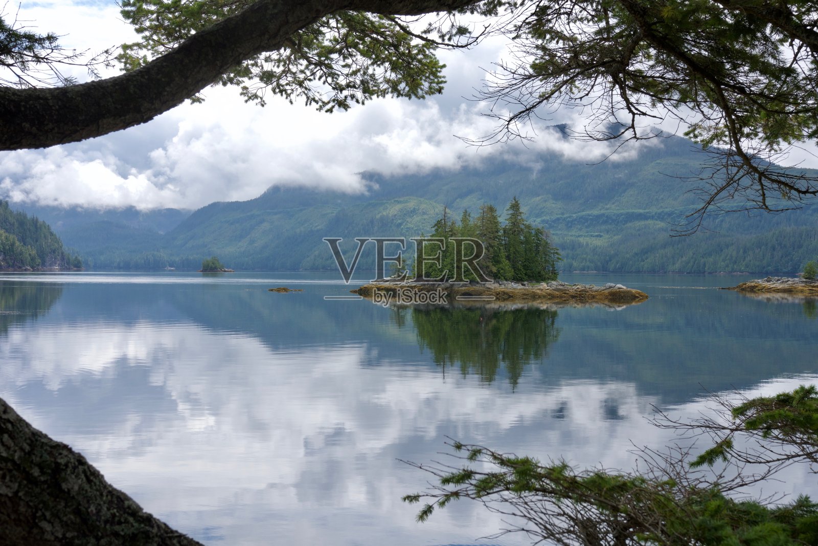 小岛在平静的海洋与山脉和明亮的云反射宁静的景象荒野照片摄影图片