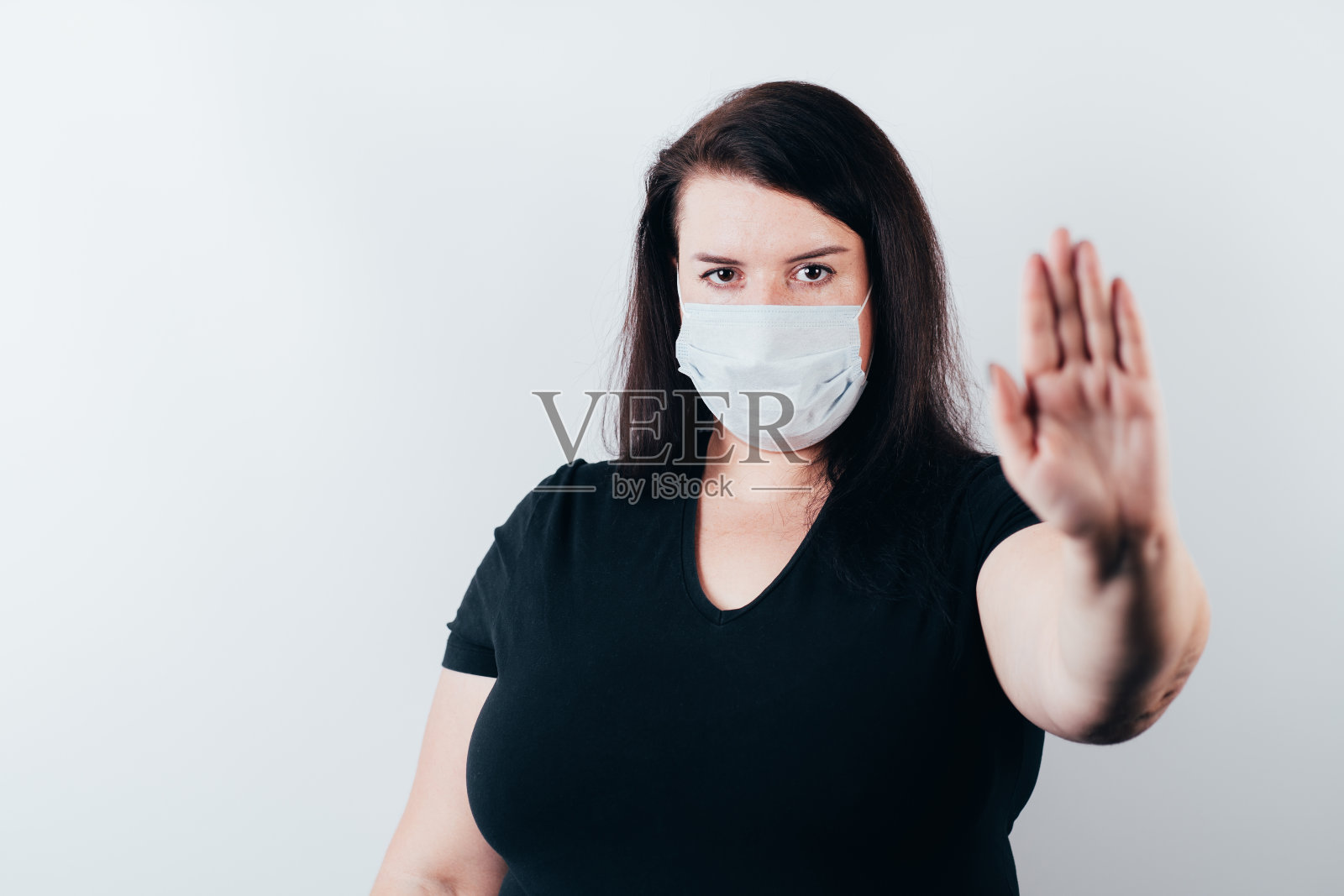 戴医用口罩的女人用拇指指着复印区照片摄影图片