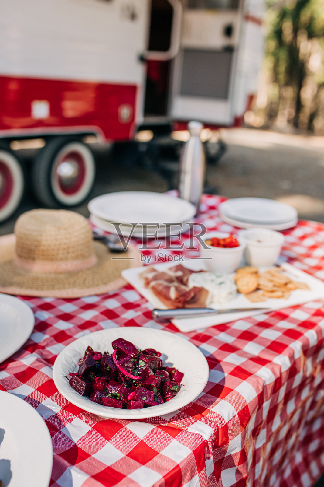 在露营地的房车旁，红白相间的桌布上放着甜菜照片摄影图片