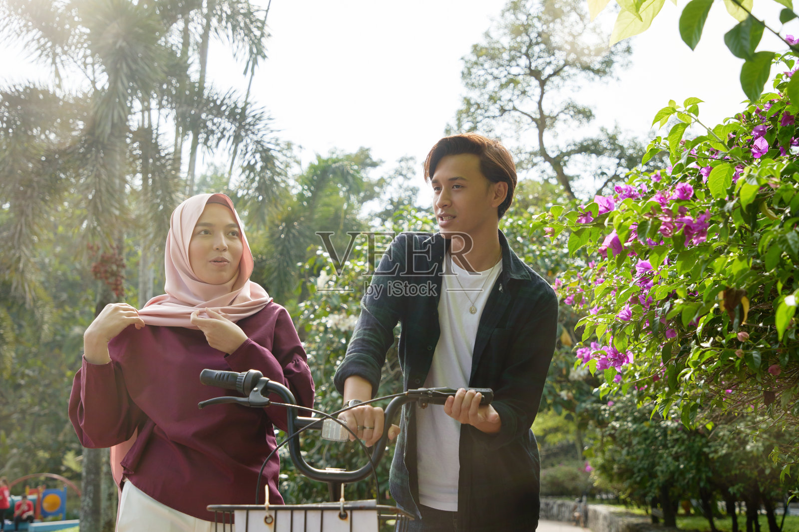 马来夫妇骑着自行车散步。他们一起在公园散步，欣赏风景照片摄影图片