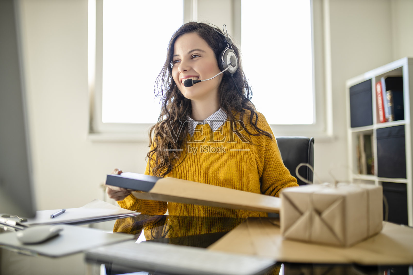 在网上购物的职业女性。她穿着休闲服，正在查看顾客的电脑地址和包装信息照片摄影图片